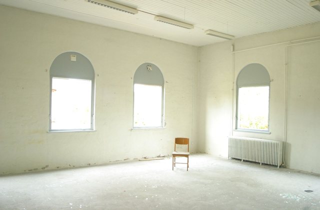 An empty room with arched windows, bare walls and a wooden floor