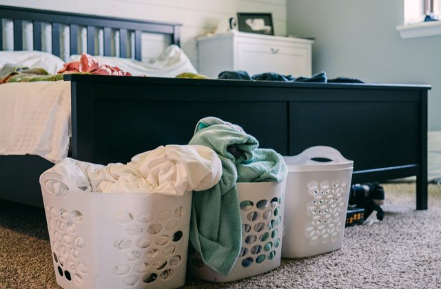 A bedroom with laundry baskets and clothes left across the floor