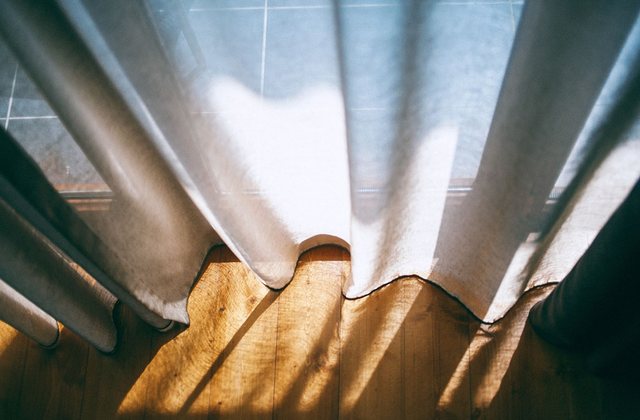 Late sunlight falling through a sheer curtain onto a wooden floor