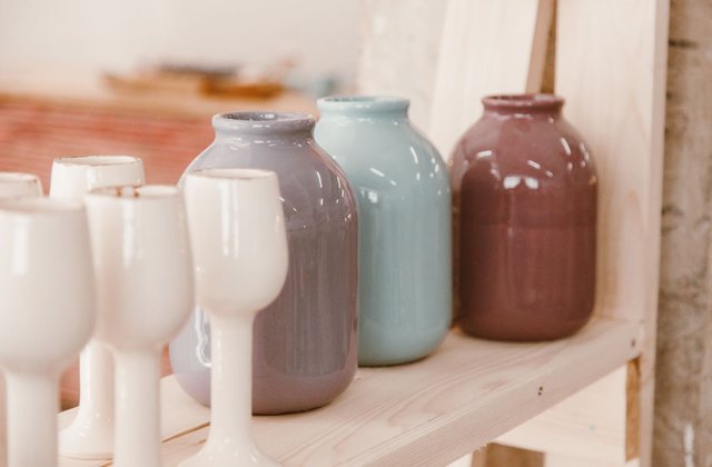 Pastel ceramic vases arranged along a plain wooden shelf