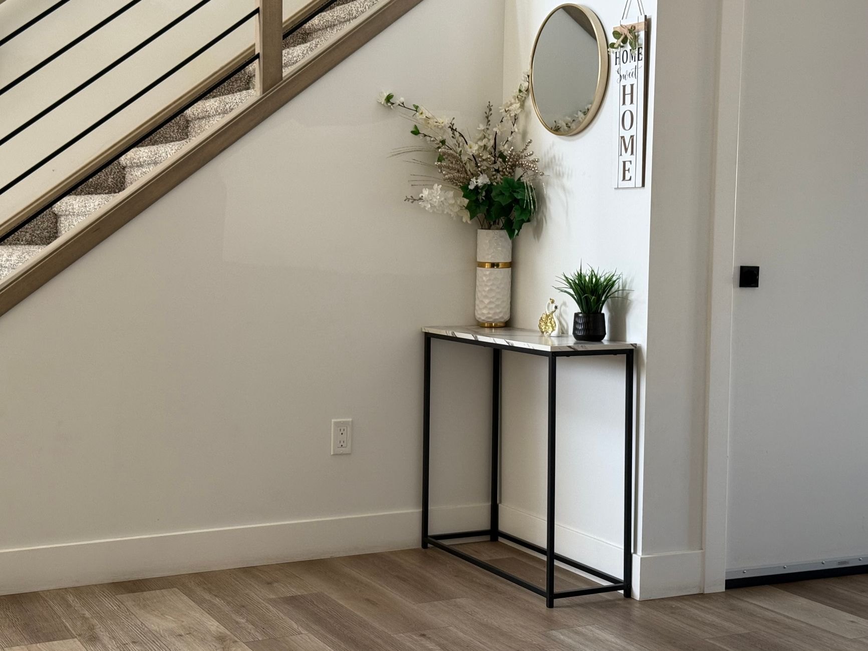 An entryway console table with a mirror above it beside a staircase