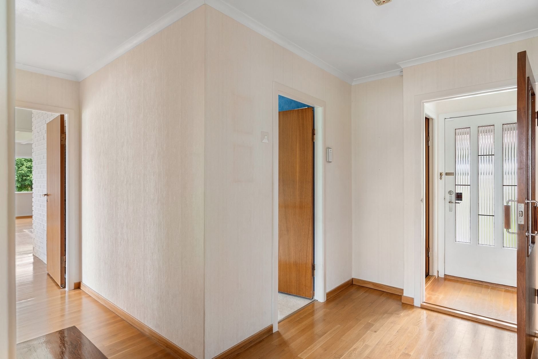 A hallway with wooden floors, open doors and light from the far end
