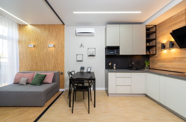 A compact studio apartment with a sofa, small table and kitchenette