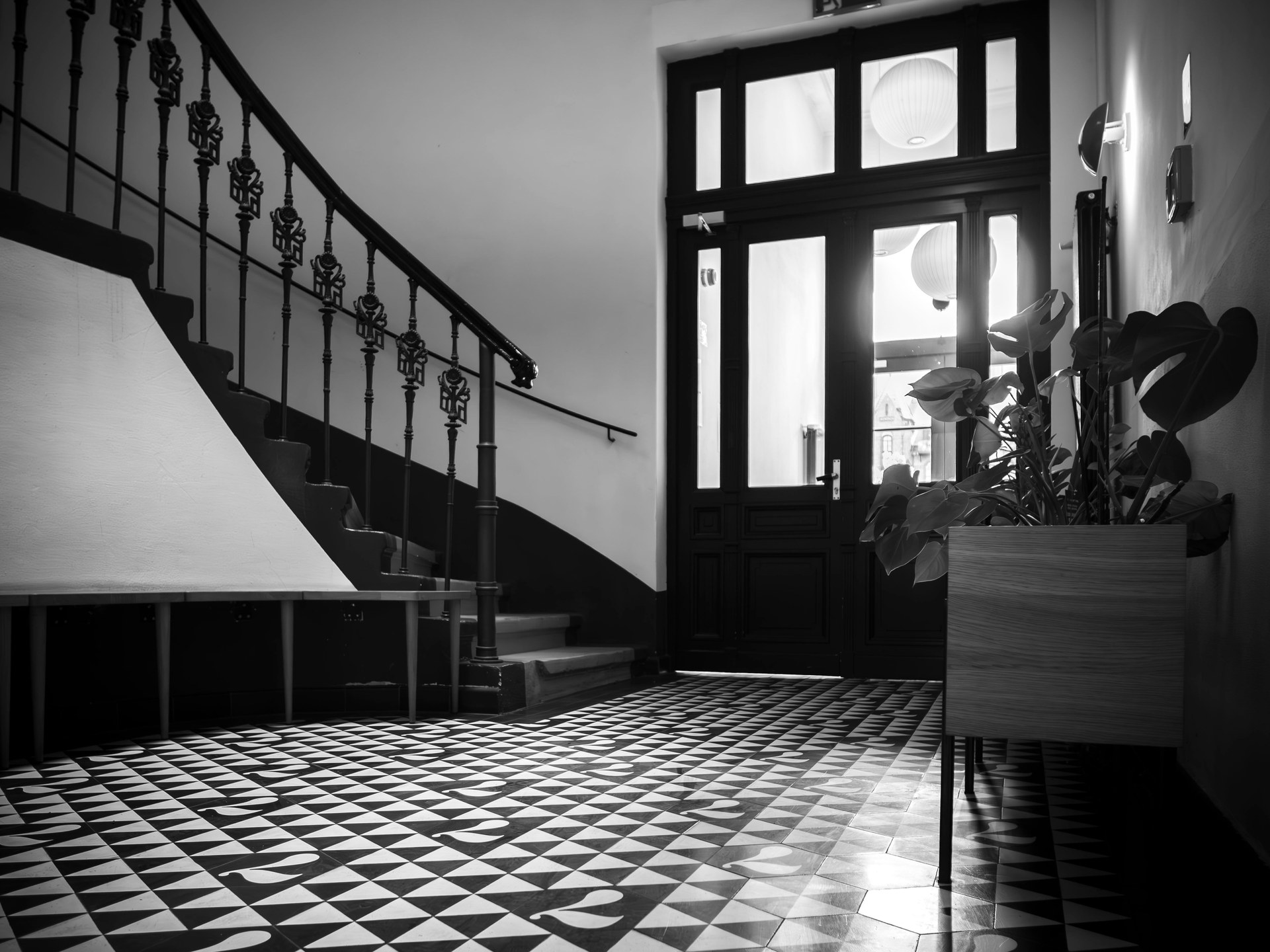 Black and white photograph of an indoor staircase in Wrocław, Poland, featuring geometric floor tiles