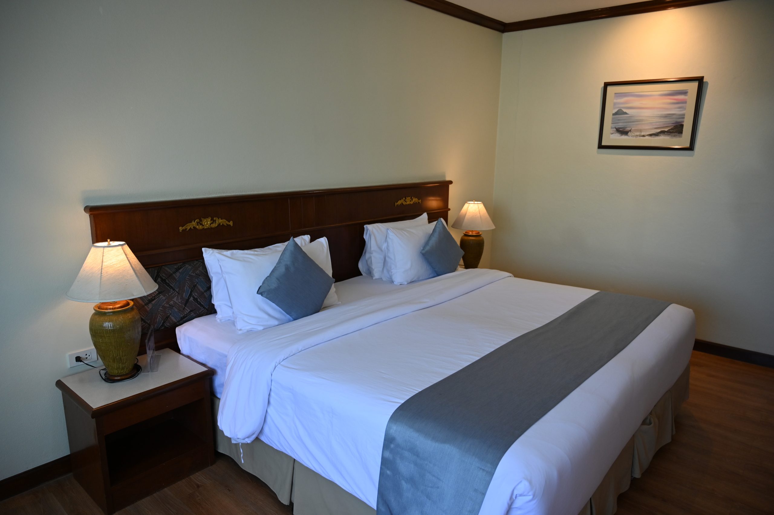 DZ6 Cozy neatly made hotel room with a king bed soft pillows bedside lamps and calming neutral decor, illustrating What Feng Shui Says About Beams and Low Ceilings