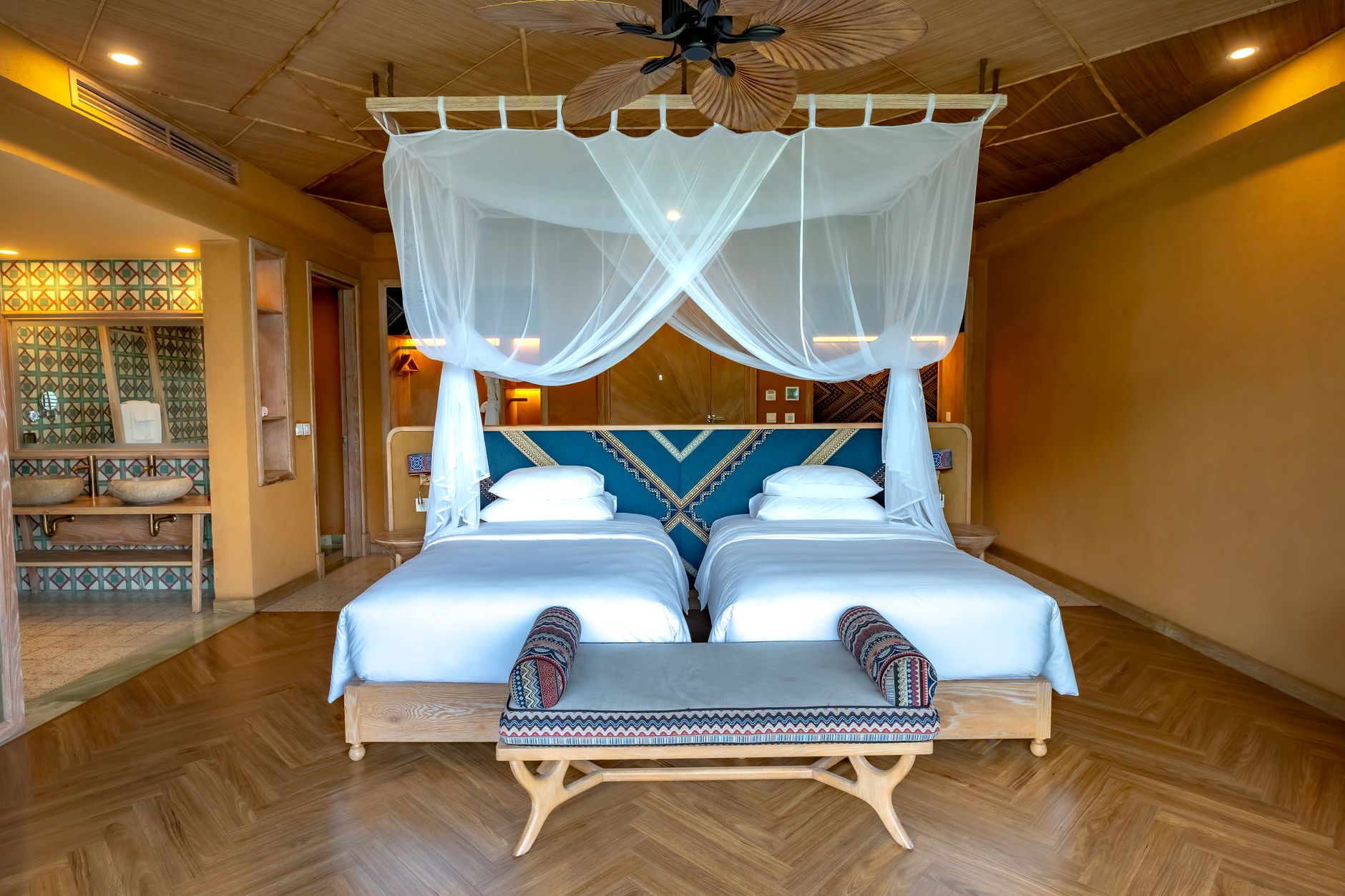 Spacious hotel room with double bed, canopy, and modern decor, perfect for tropical getaways, illustrating Bed Under a Window in Feng Shui: What It Means