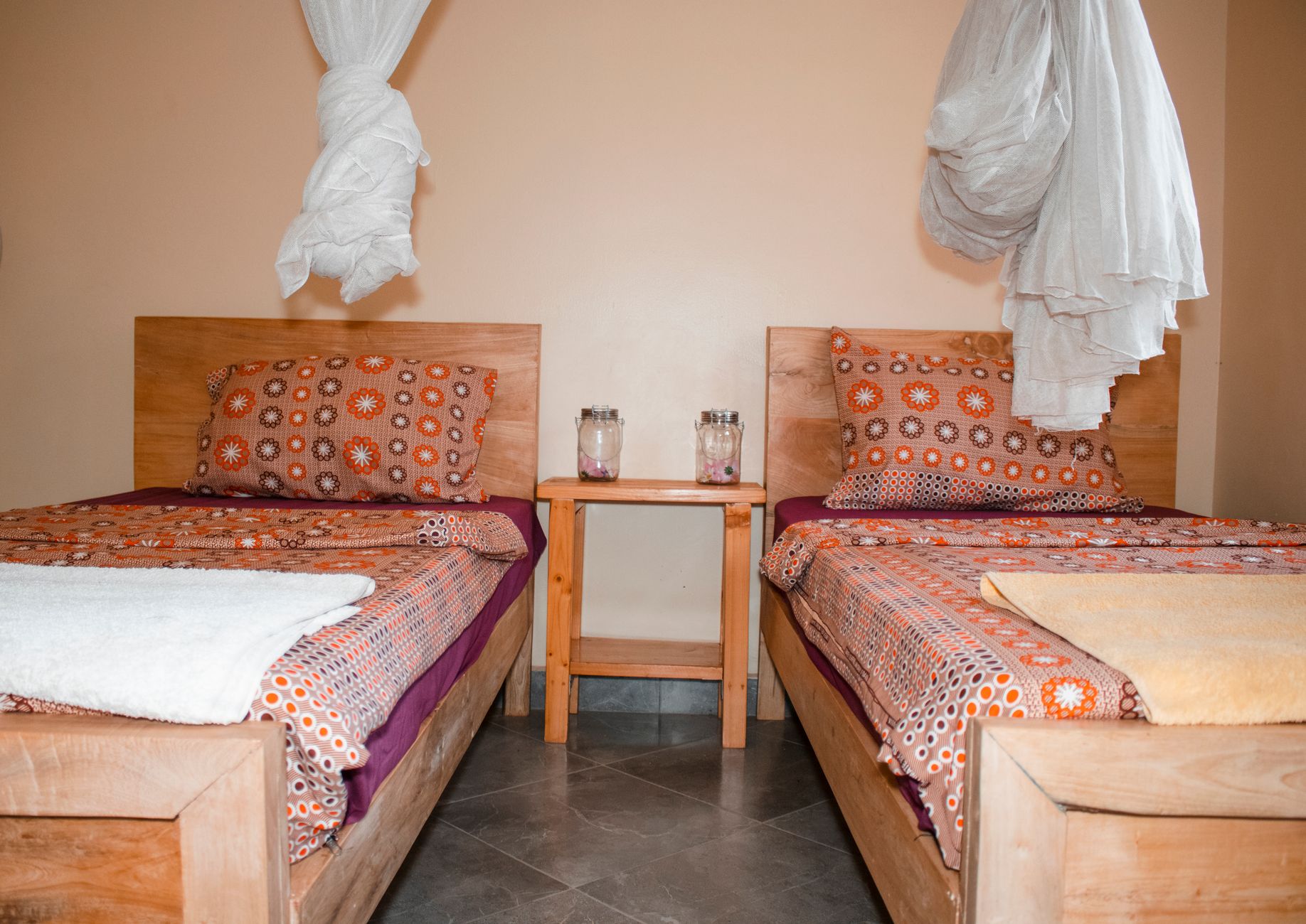 Comfortable twin bedroom with mosquito nets and colorful bedding in Kampala, Uganda, illustrating Bed Under a Window in Feng Shui: What It Means