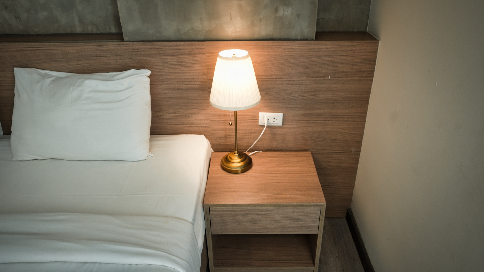 Elegant bedroom setup with a lamp on a wooden nightstand, creating a cozy ambiance, illustrating Bedroom Above a Garage: What Feng Shui Actually Says