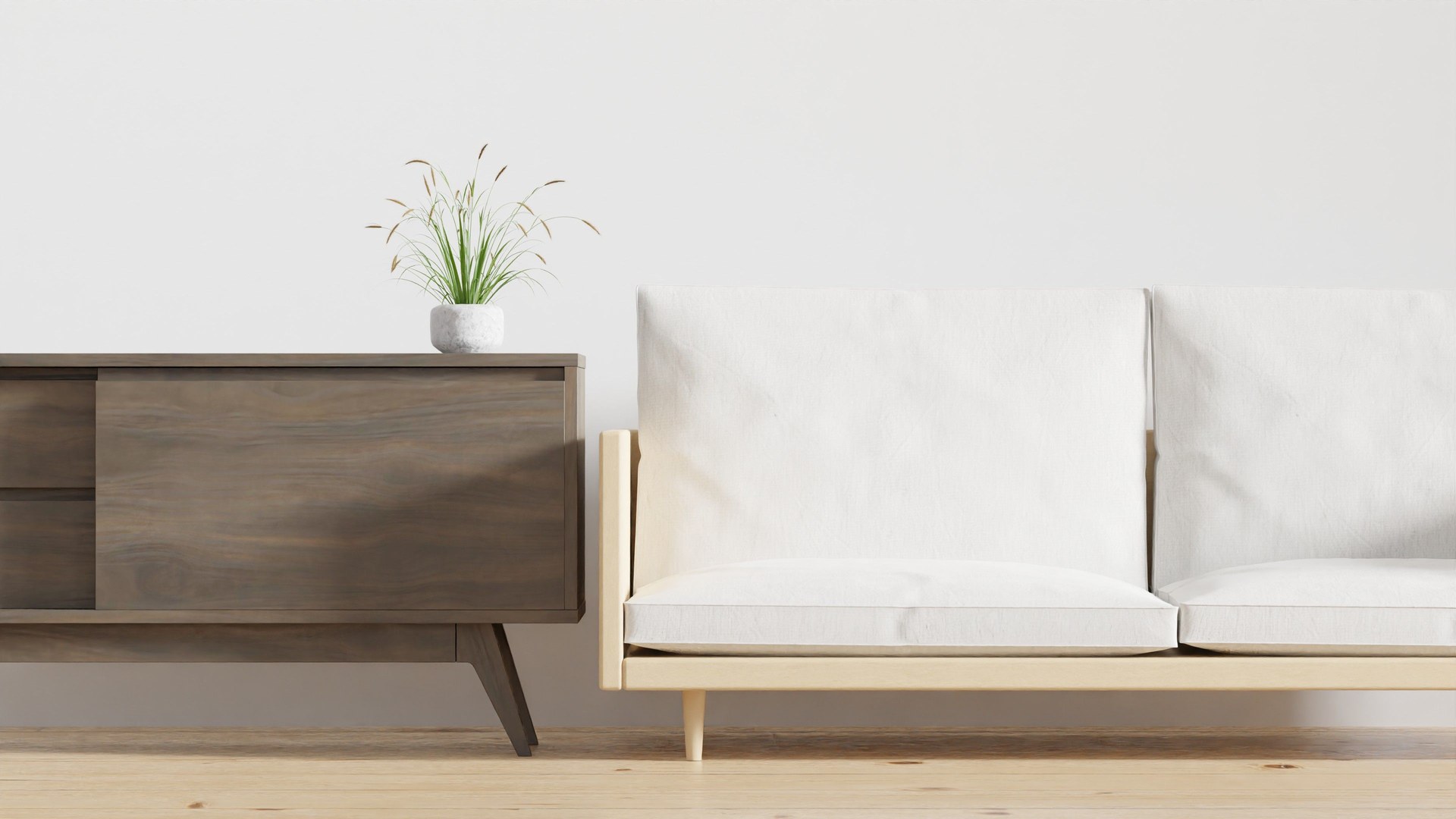 A minimalist living room features a chic wooden console with a potted plant and a cozy beige sofa