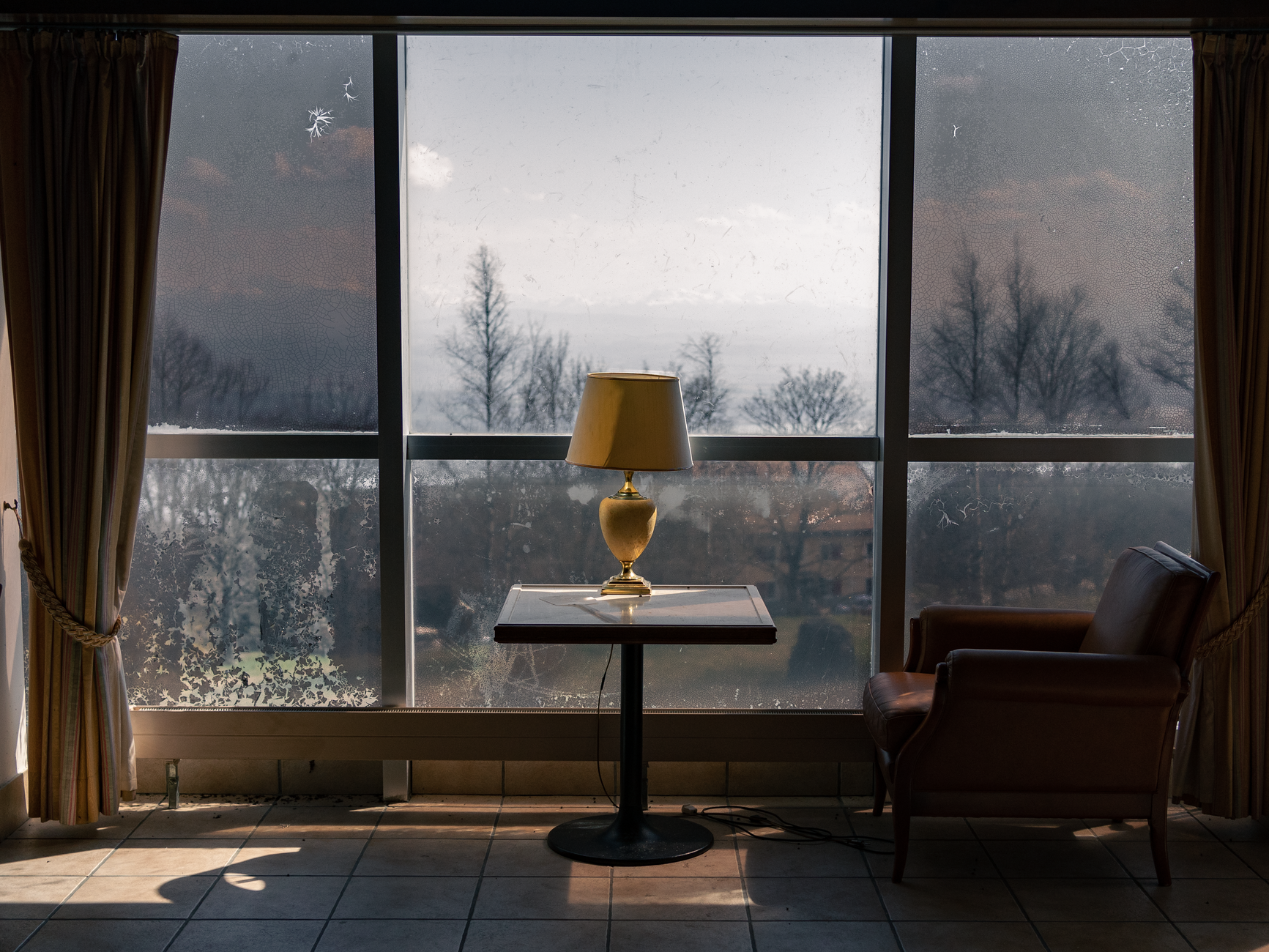 Interior view with a lamp on table near large window showcasing outdoor scenery, illustrating What Does Feng Shui Say About Blocked Windows