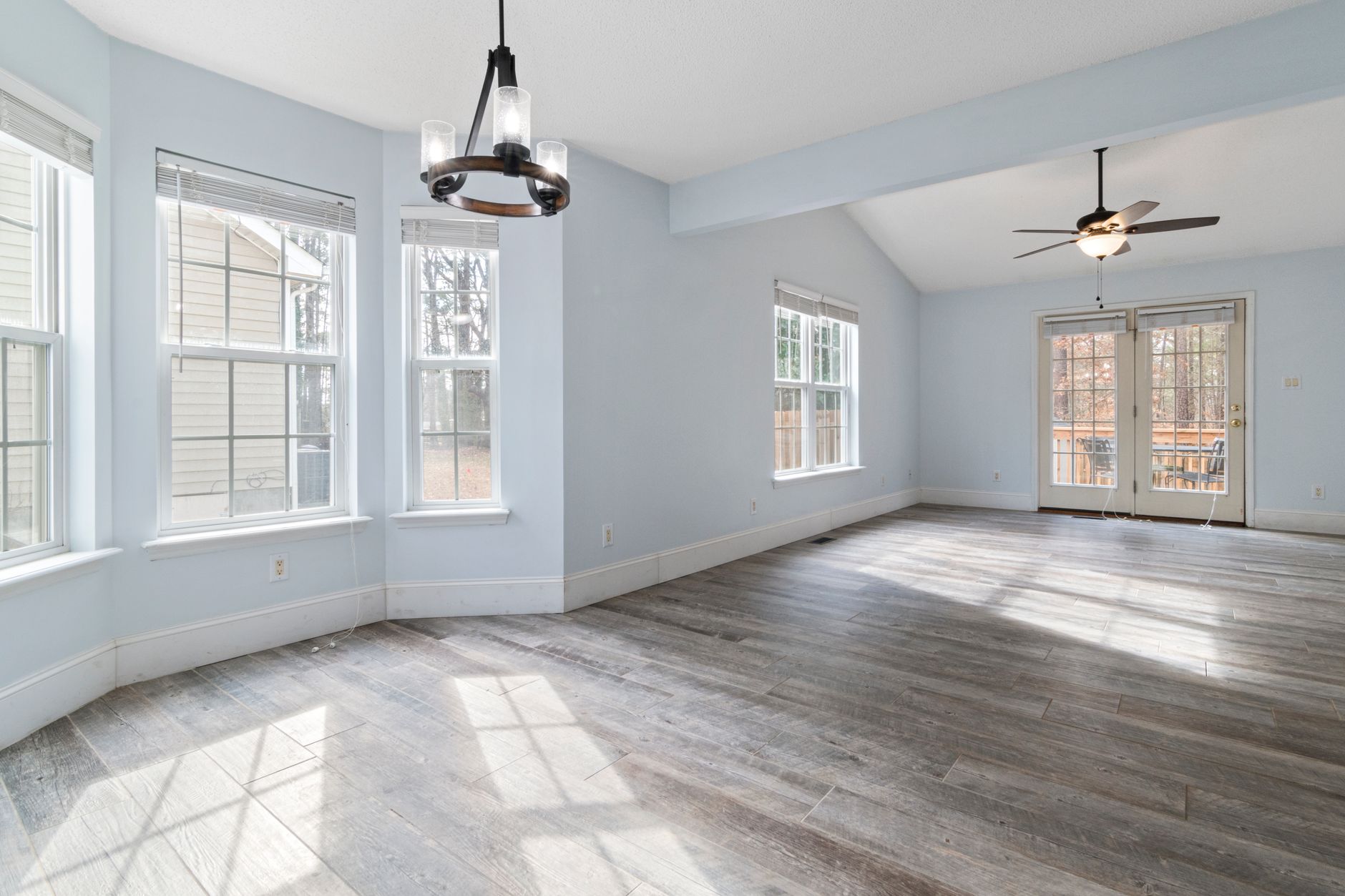 Bright empty living room with wooden floor and ceiling fan, ideal for interior design use, illustrating What Does Feng Shui Say About Blocked Windows