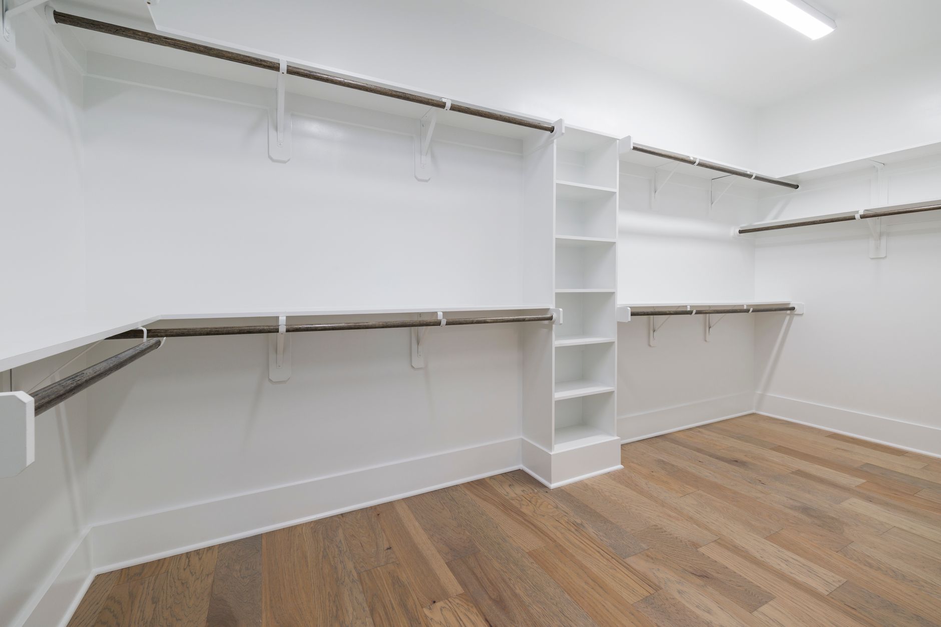 Modern empty walk in closet with wooden flooring and white shelving, illustrating Feng Shui and Books: What Open Shelving Really Means