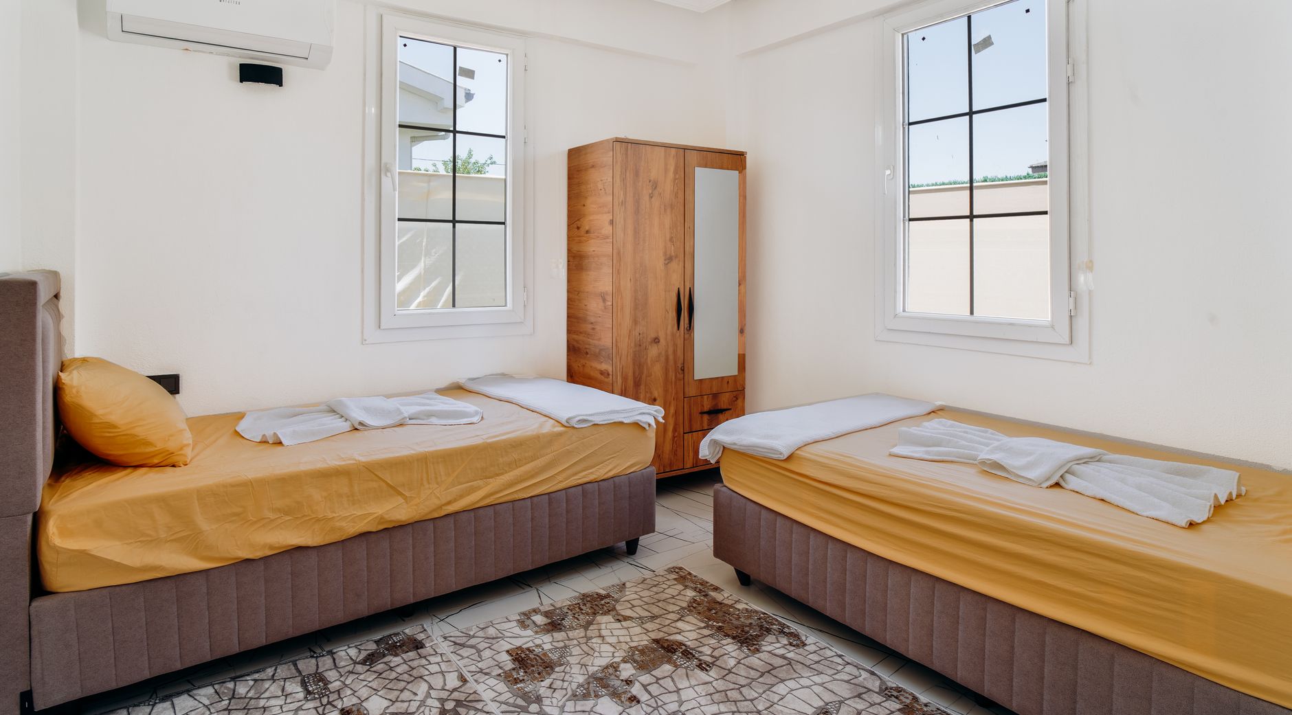 A minimalist bedroom featuring two neatly made twin beds with yellow sheets, illustrating Can't Move the Bed? What Feng Shui Actually Suggests