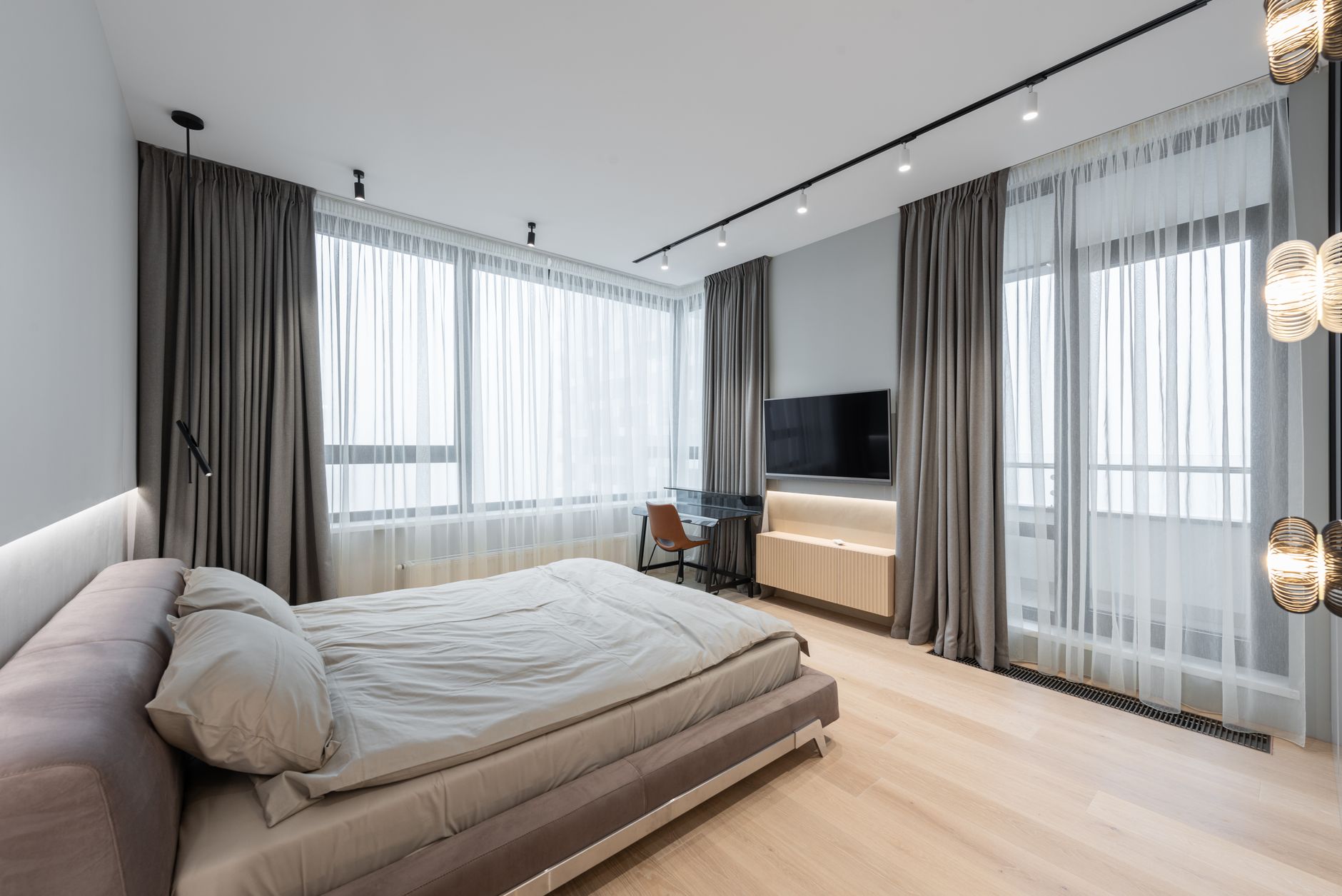 Interior of modern light bedroom with bed next to TV with curtains on windows and table with chair, illustrating What Does Feng Shui Say About a Children's Bedroom