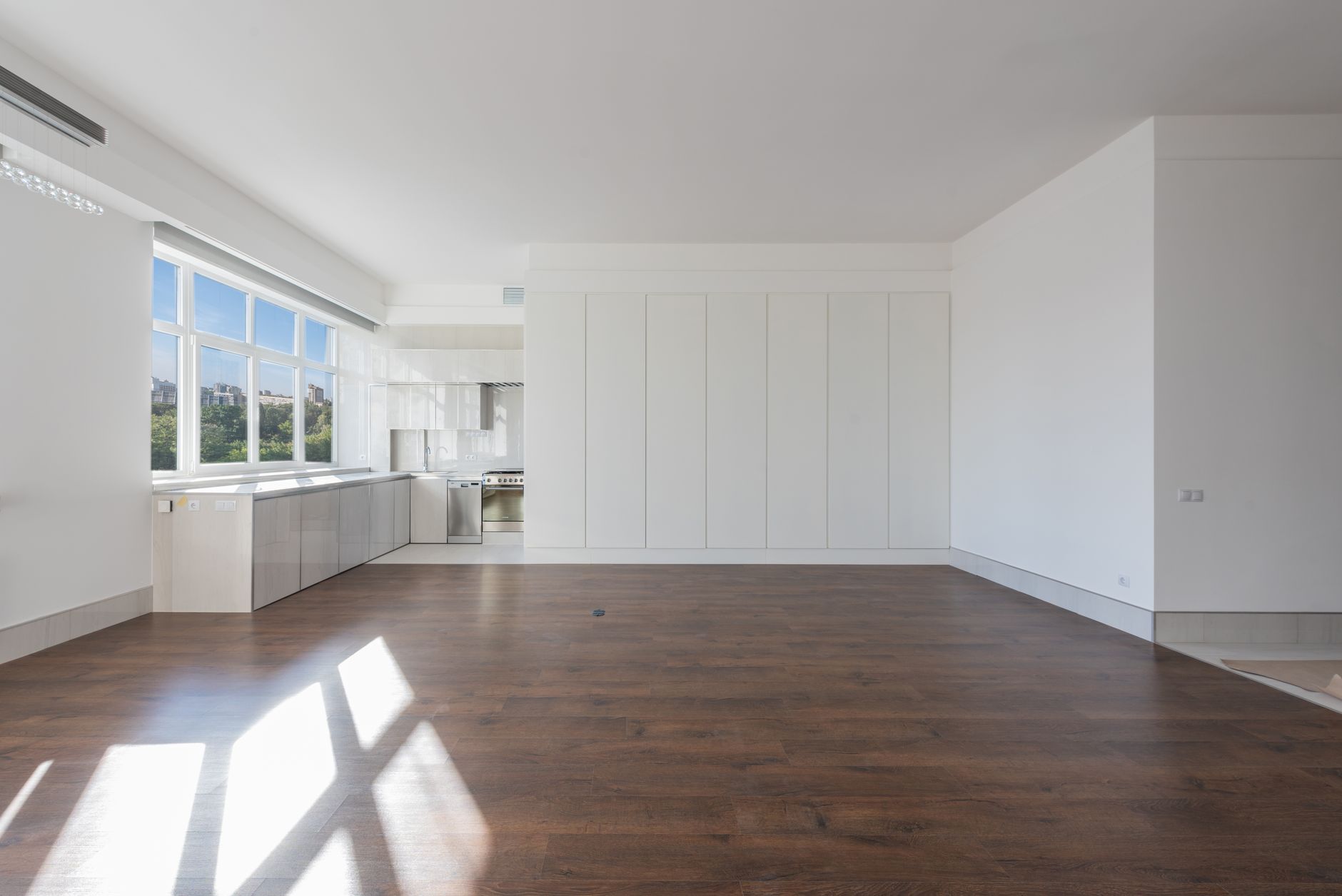 Bright and spacious modern kitchen interior featuring wooden floors and white cabinetry, illustrating What Does Feng Shui Say About Curtains and Window Coverings