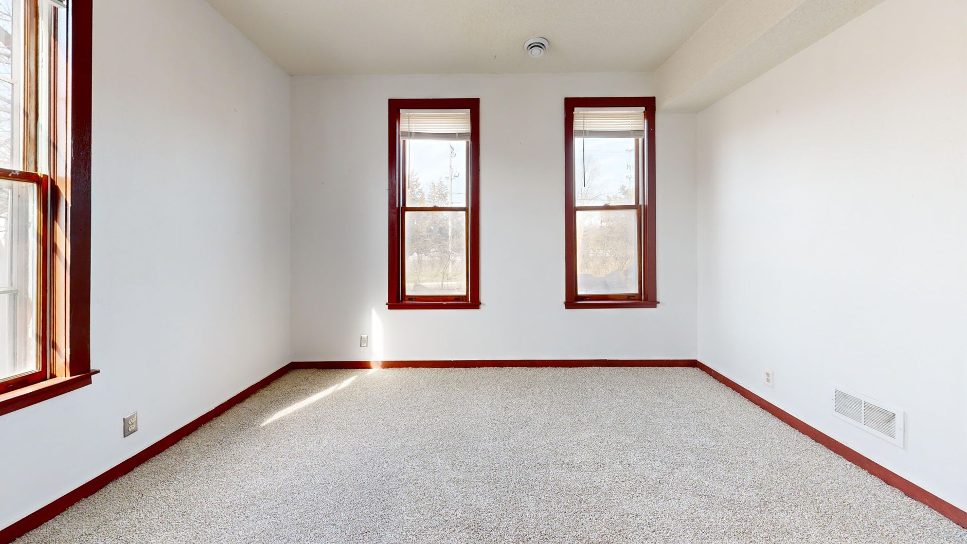 Spacious empty room with large red trimmed windows and white walls, perfect for interior design, illustrating What Does Feng Shui Say About Curtains and Window Coverings