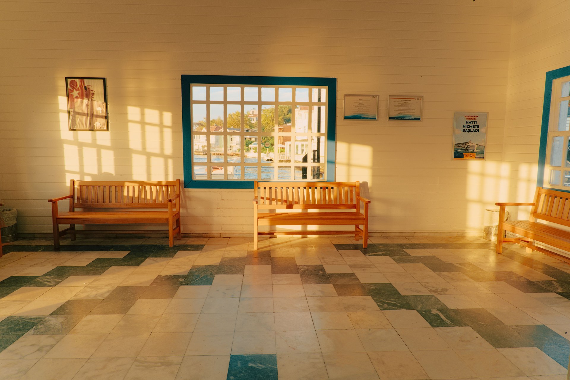 Warm sunlight filters through windows into a waiting room with wooden benches and tiled floor