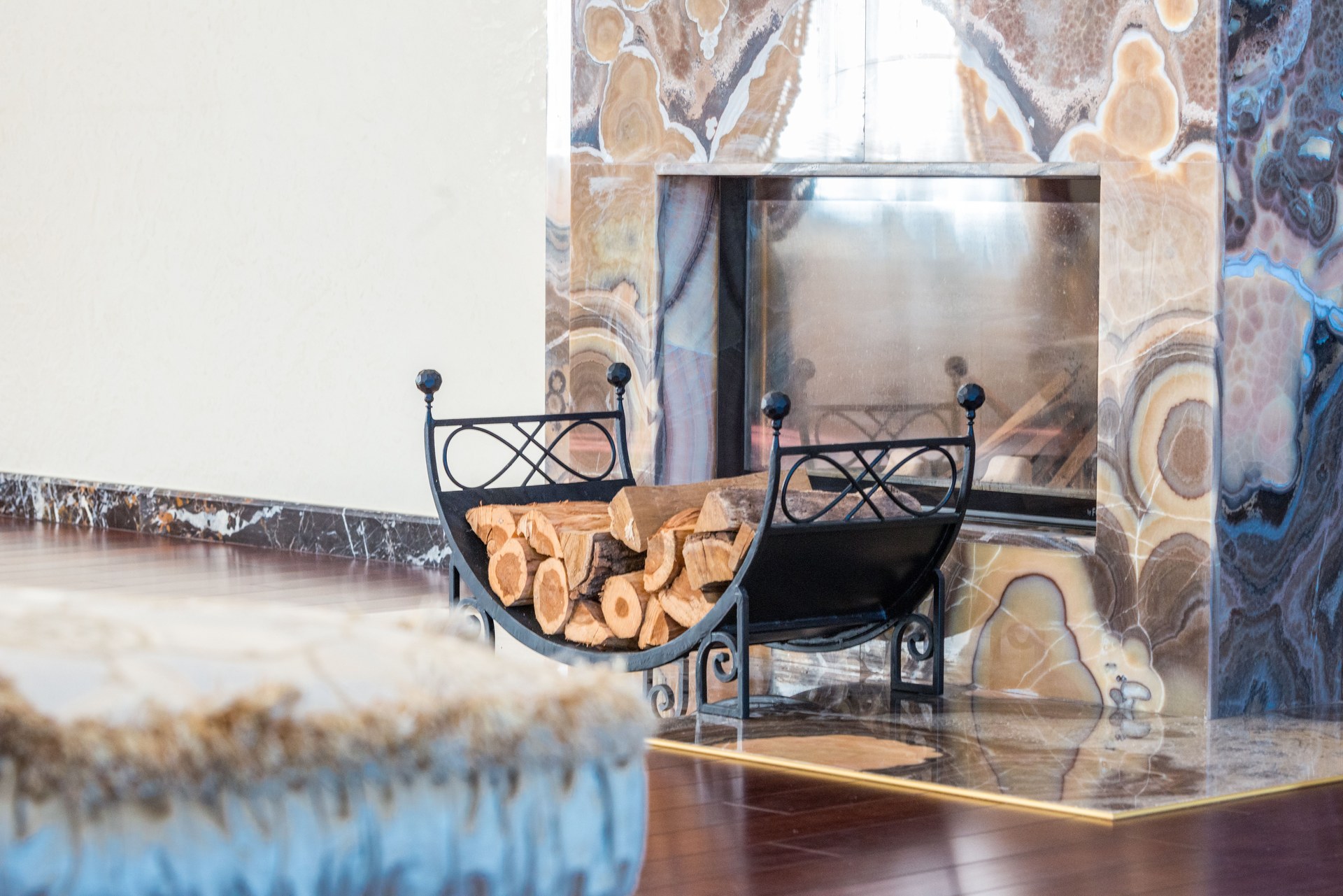 Interior of modern lounge decorated with marble fireplace with patterns and black wood rack