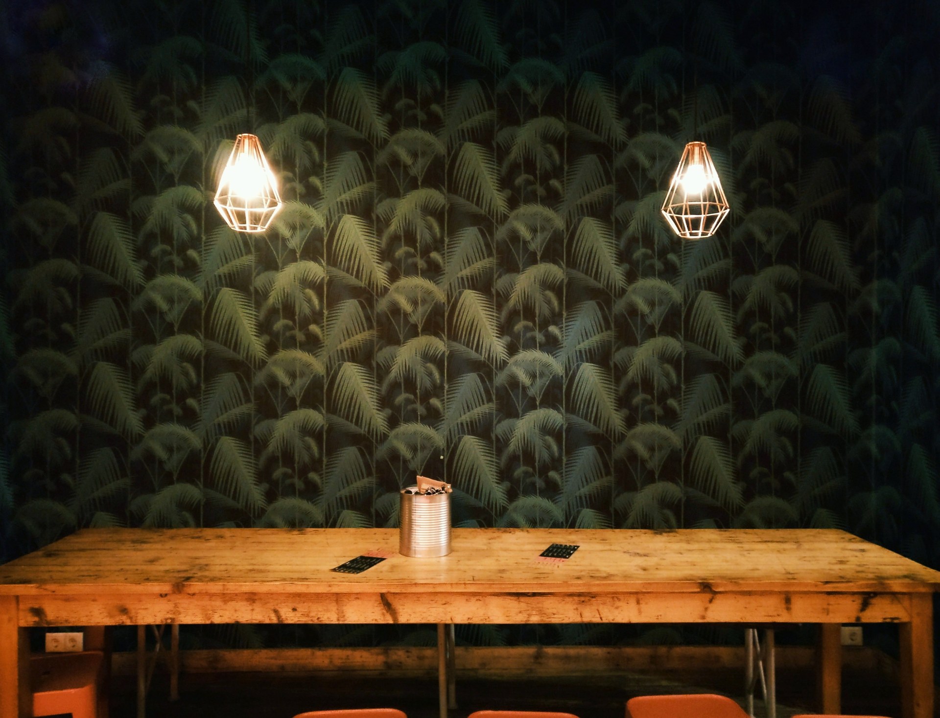 Rustic interior featuring geometric pendant lamps and a large wooden table against a patterned wall
