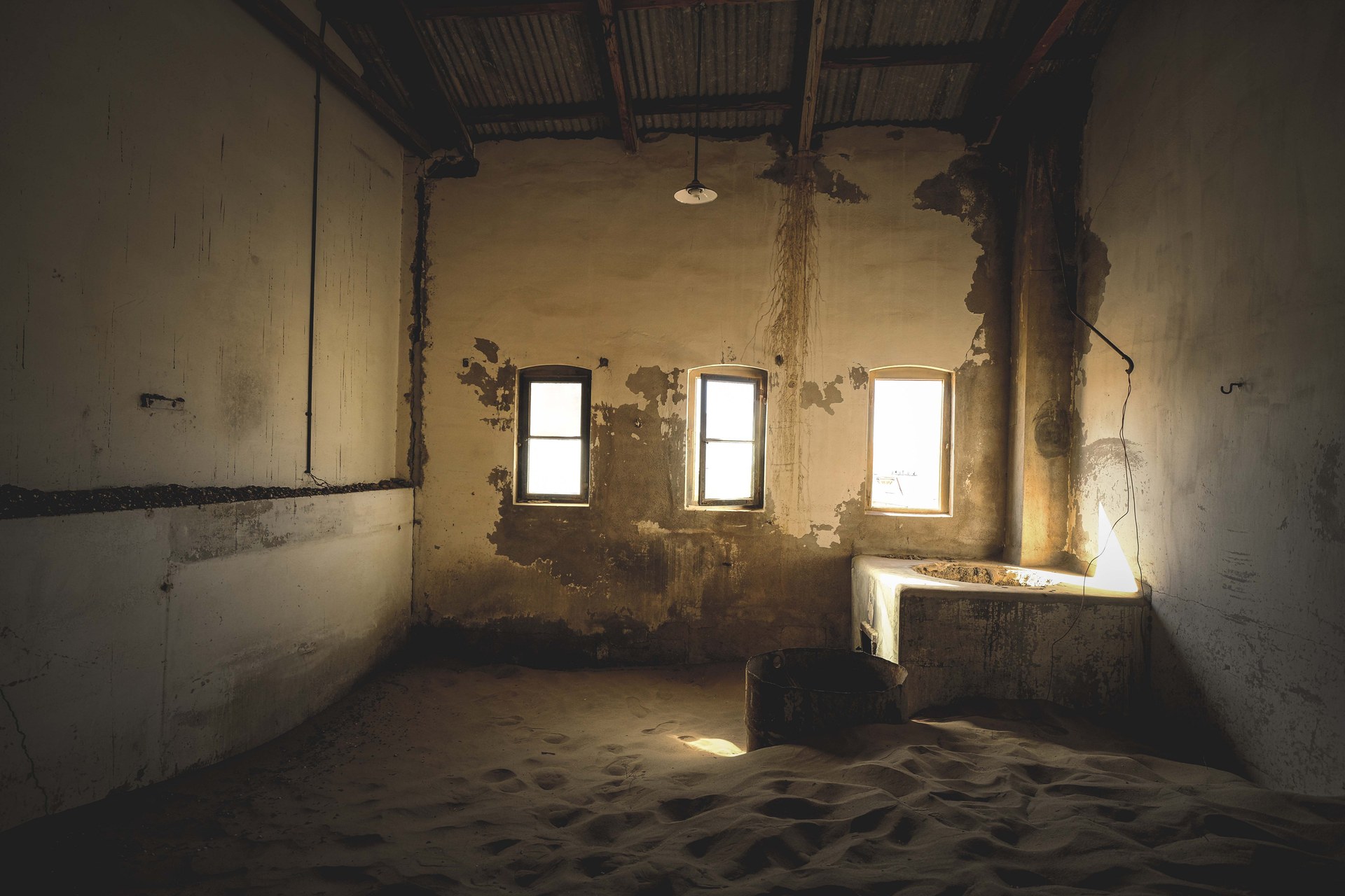Eerie, abandoned room filled with sand, showcasing decay and vintage architecture