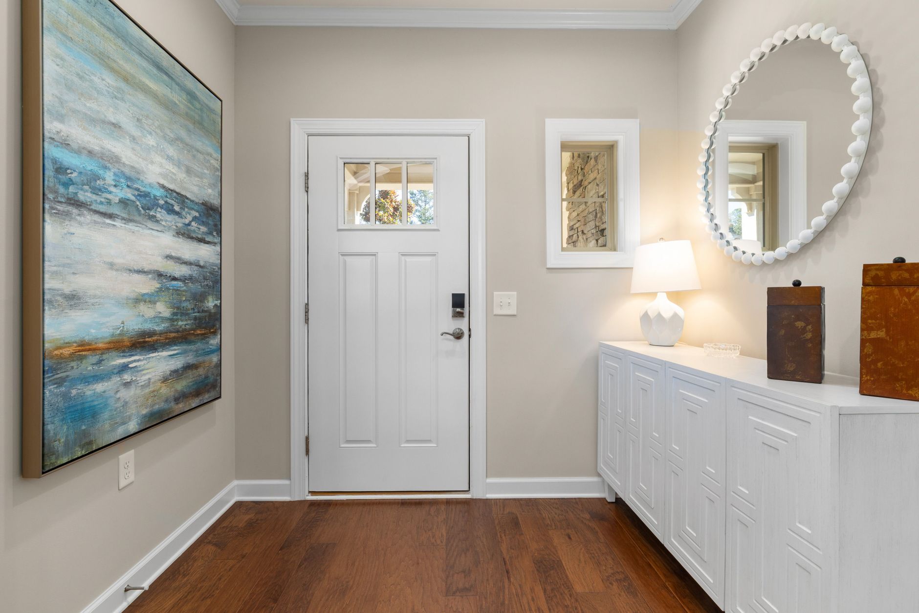Bright and modern entryway featuring abstract art, a white door, and elegant decor. Ideal for contemporary living spaces, illustrating What Should Be in an Entryway, and What Shoul