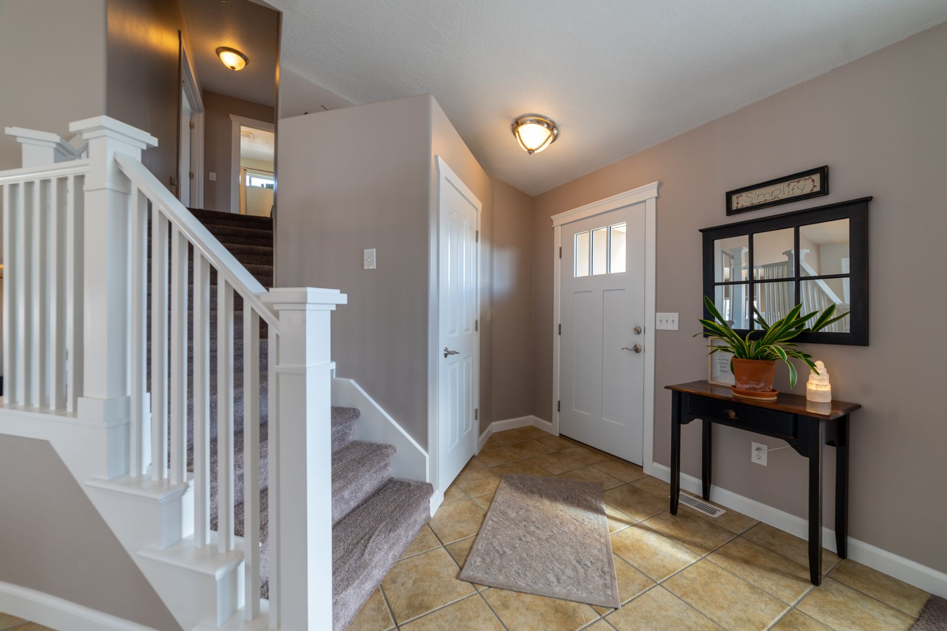 Bright entryway featuring stairs, a door, and stylish interior design elements, illustrating What Should Be in an Entryway, and What Shouldn't