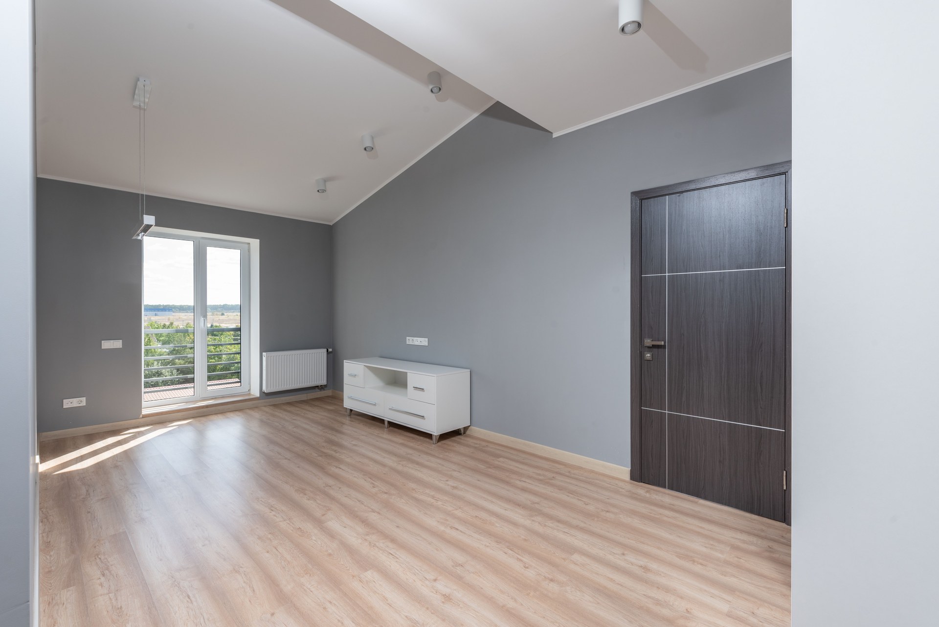 Bright and empty modern room with hardwood floors and large window view