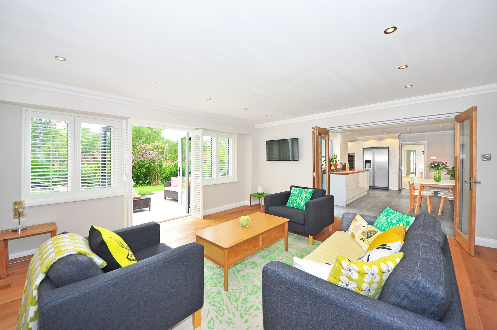 Modern living room with open plan kitchen and garden view, bright and airy ambiance, illustrating What Does Feng Shui Say About a TV in the Living Room