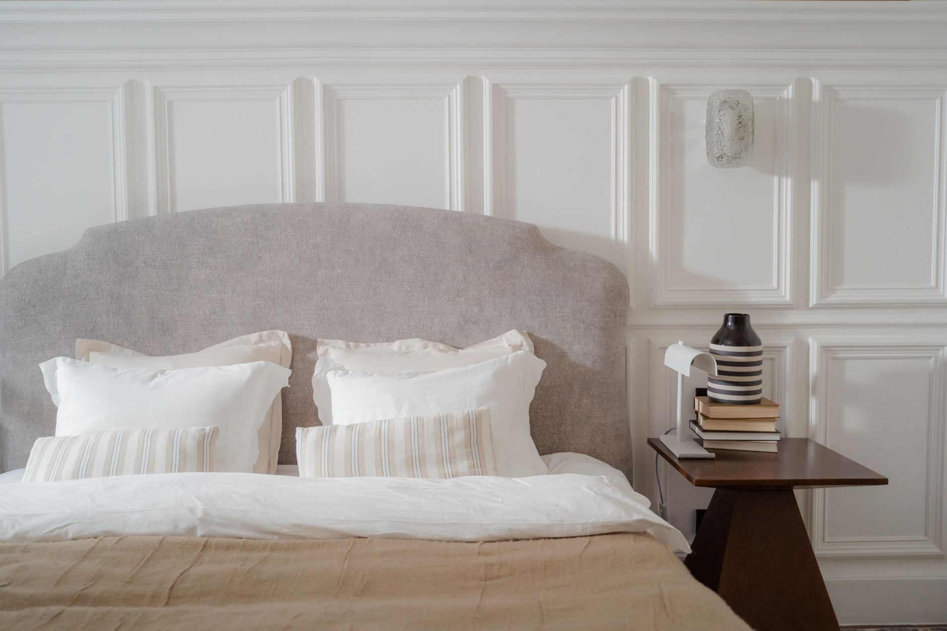 Elegant bedroom with cozy bed and stylish side table. Features neutral tones and soft lighting, illustrating Furniture Against Walls: What Feng Shui Actually Says