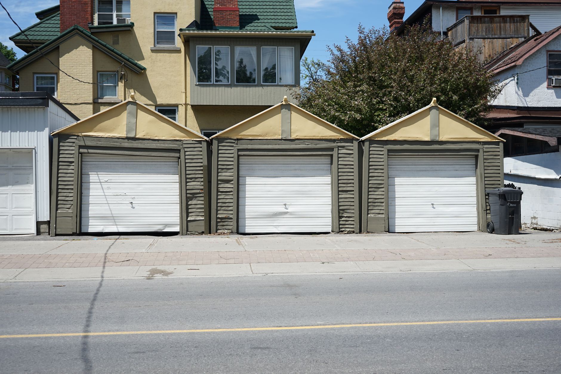 Row of three traditional residential garages with unique roof design on a sunny day, illustrating Garage Facing the Street: What Feng Shui Actually Says