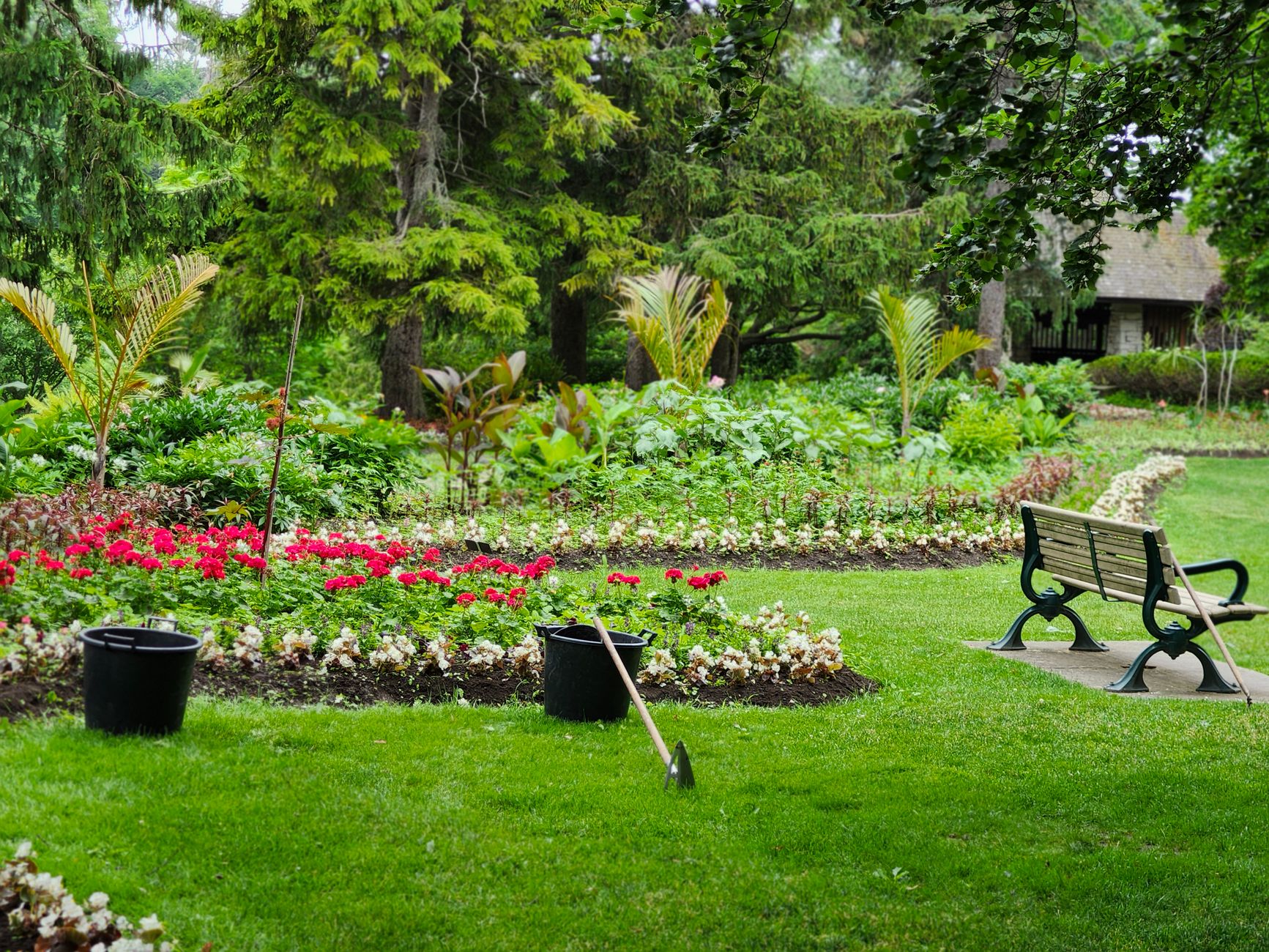 Tranquil park scene featuring lush greenery, a flower garden, and an empty bench, illustrating What Feng Shui Actually Says About a Garden Gate