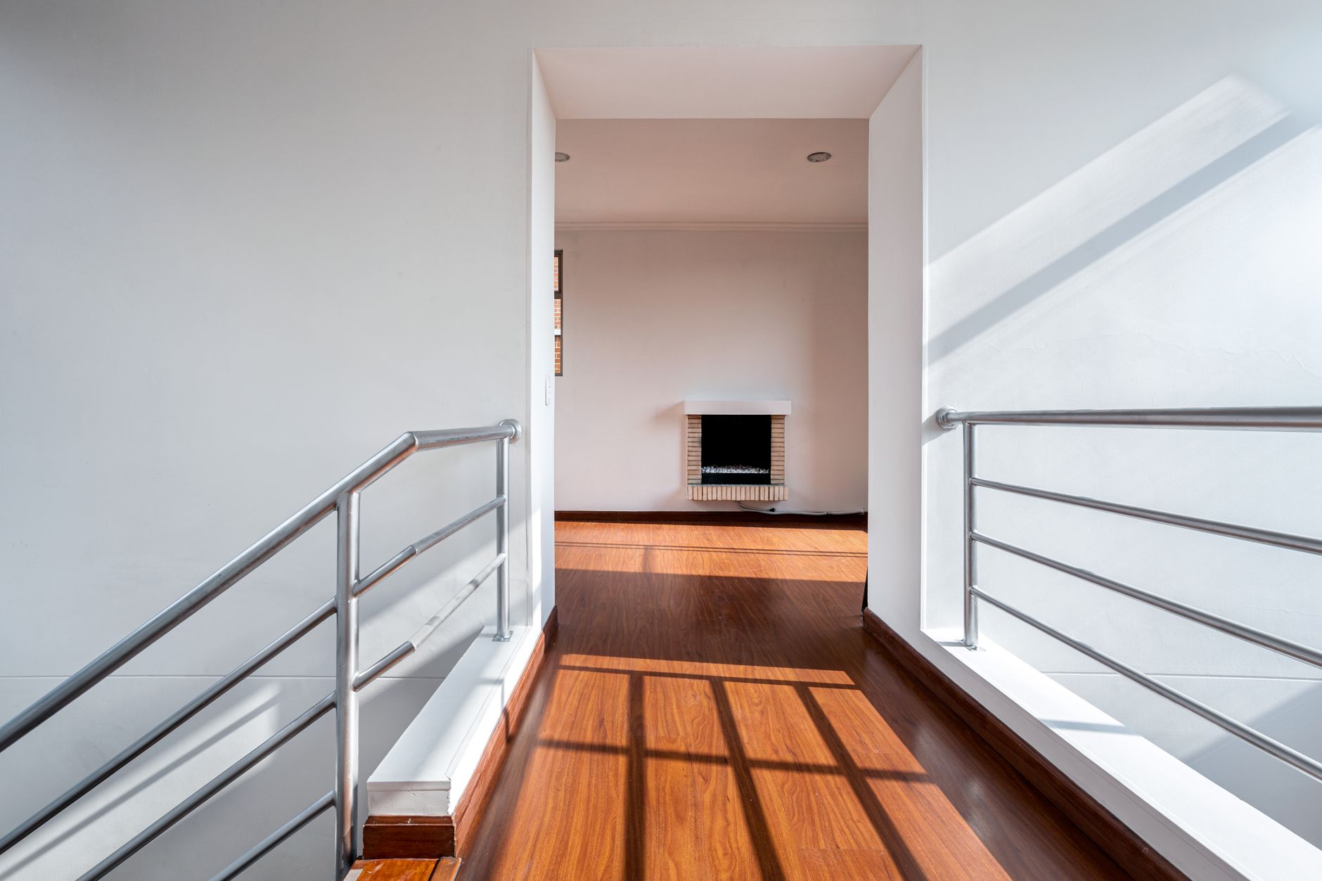 Bright and minimalistic hallway with railings and wooden floor in Bogotá apartment, illustrating How Should a Hallway Be Treated? A Feng Shui Guide
