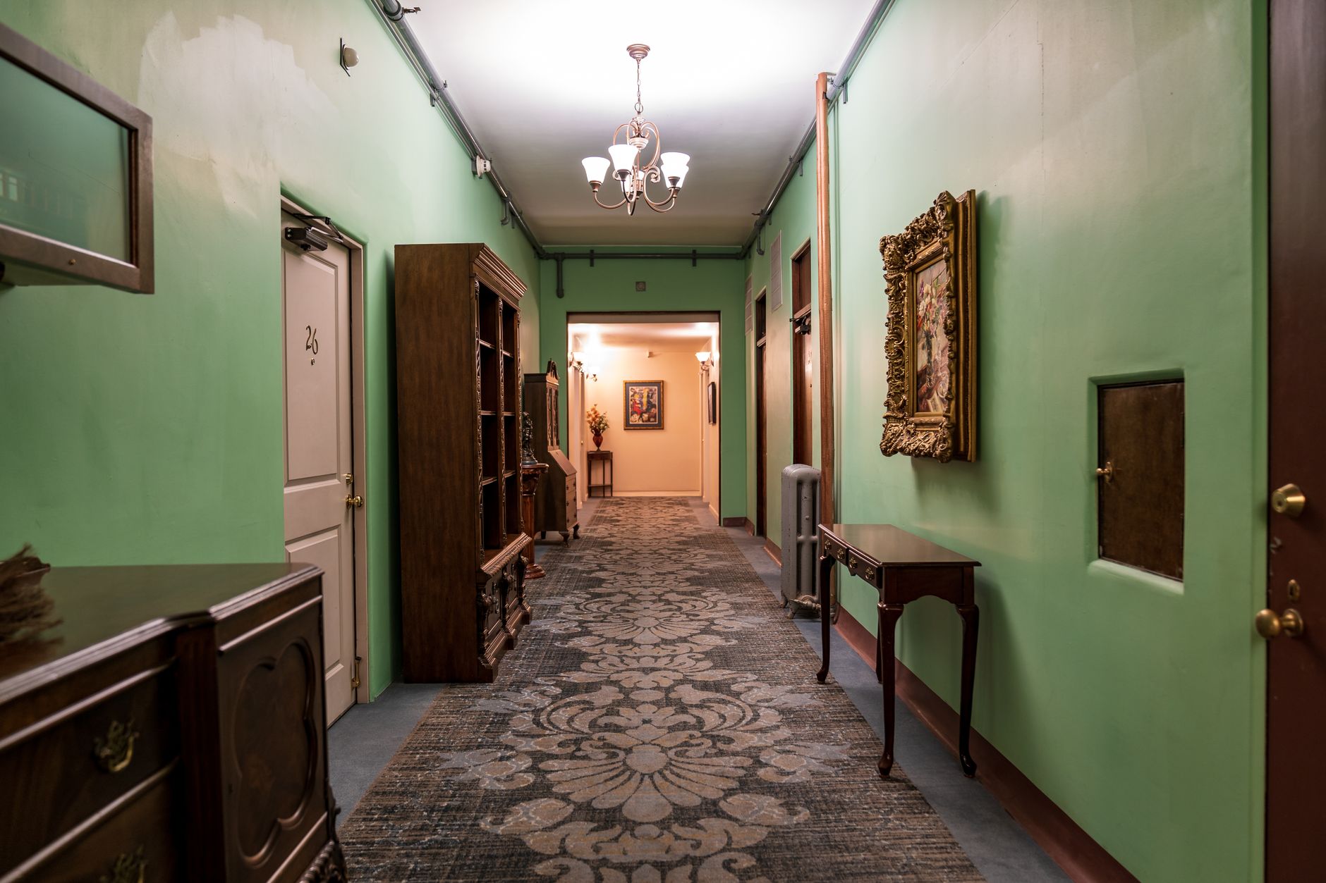A vintage style hotel hallway adorned with classic furnishings and a chandelier, illustrating How Should a Hallway Be Treated? A Feng Shui Guide