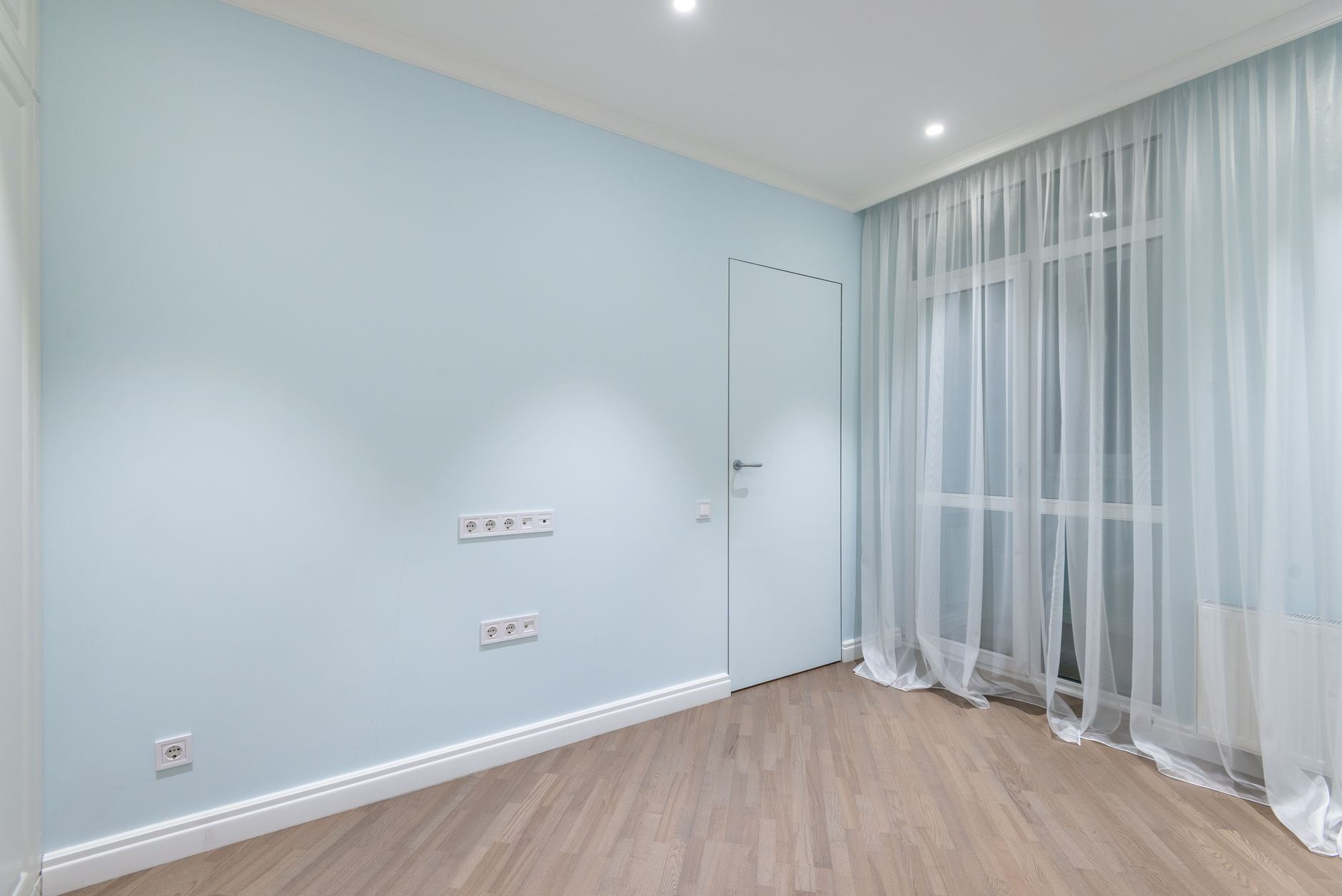 Interior of spacious empty room with beige laminate and white walls under luminous lamps, illustrating Home Viewing Feng Shui Checklist: What to Look At