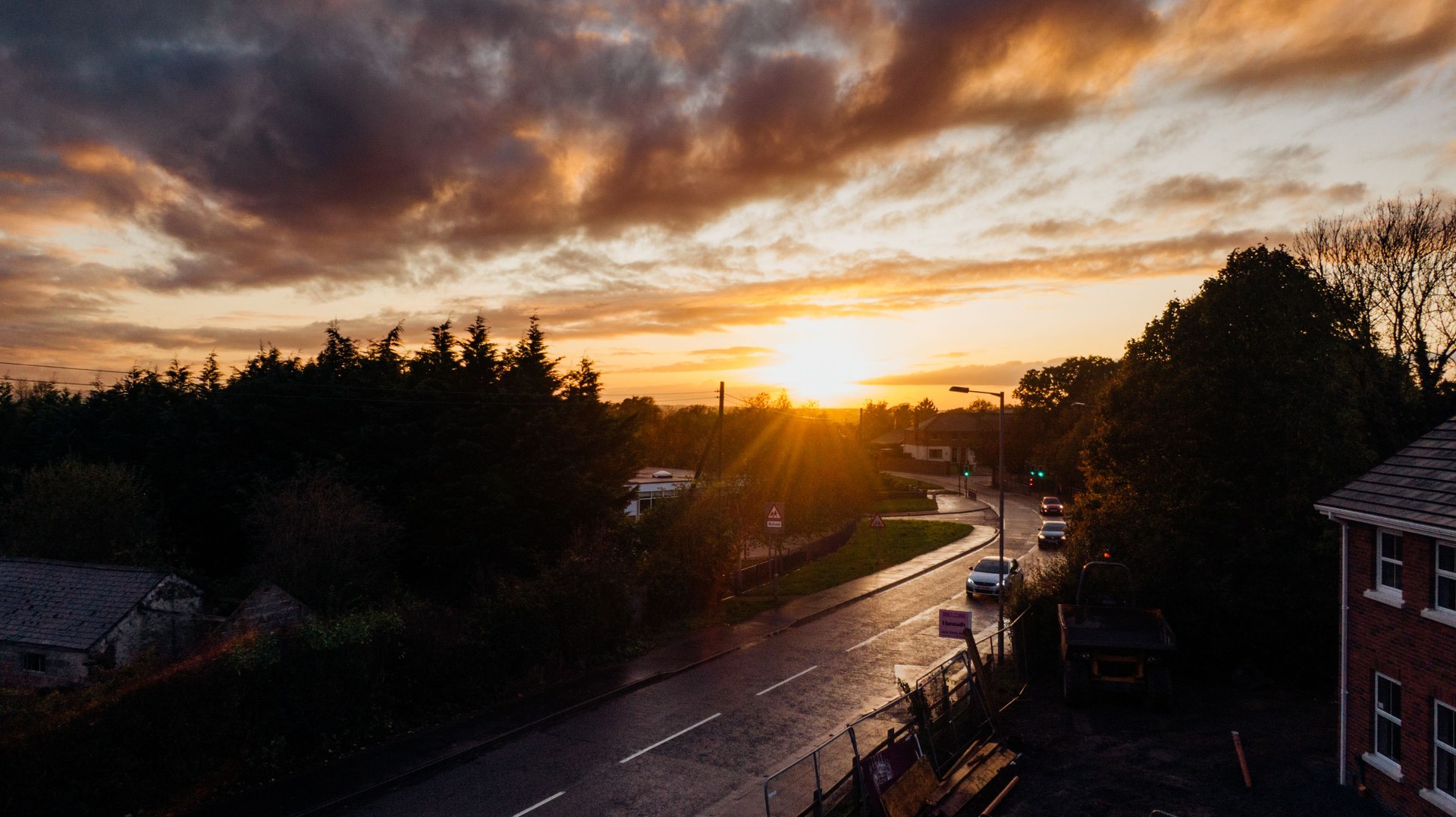 Scenic sunset view over a quiet urban street surrounded by trees and buildings, casting warm hues