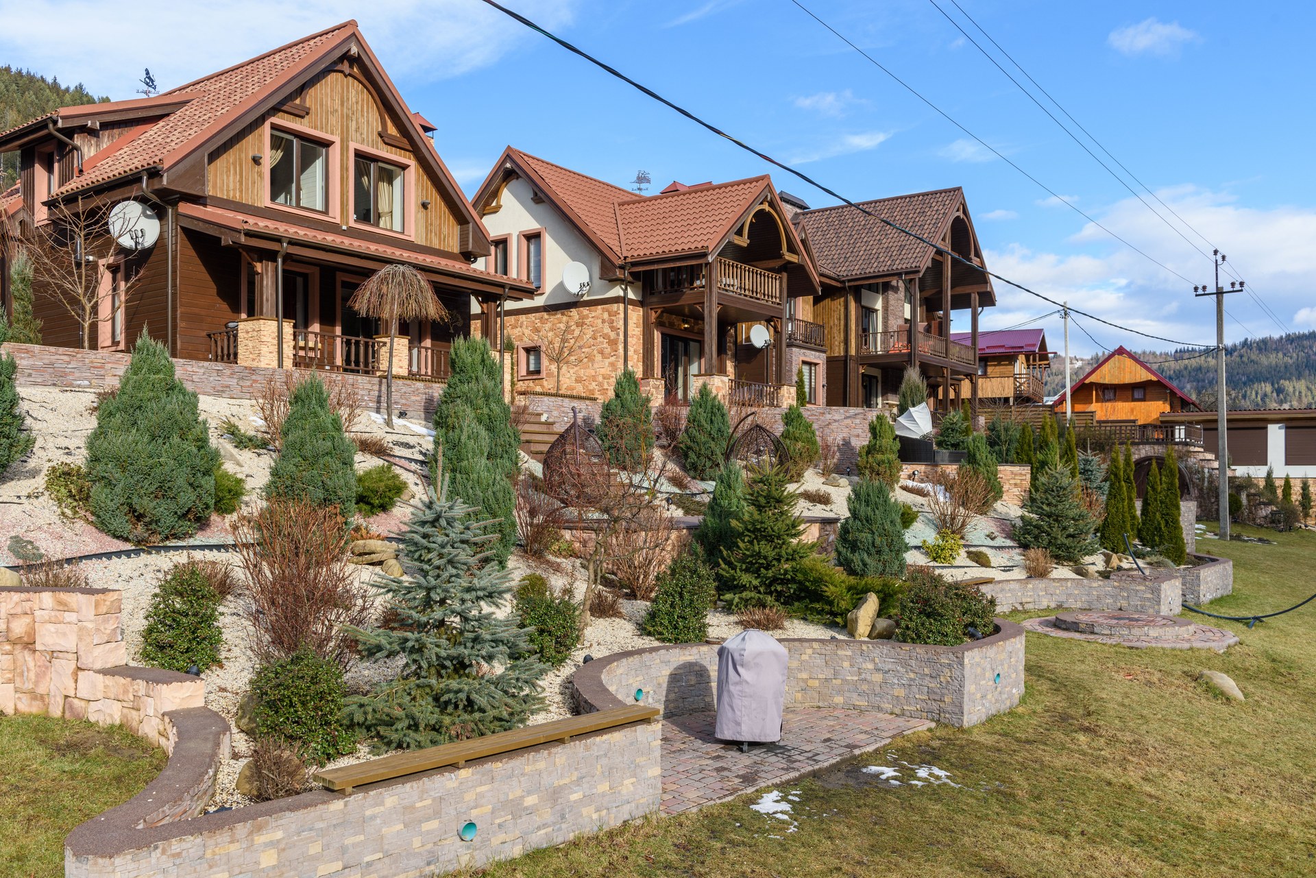 Rustic houses with sloped roofs and landscaped gardens under clear blue skies. Ideal for real estate visuals