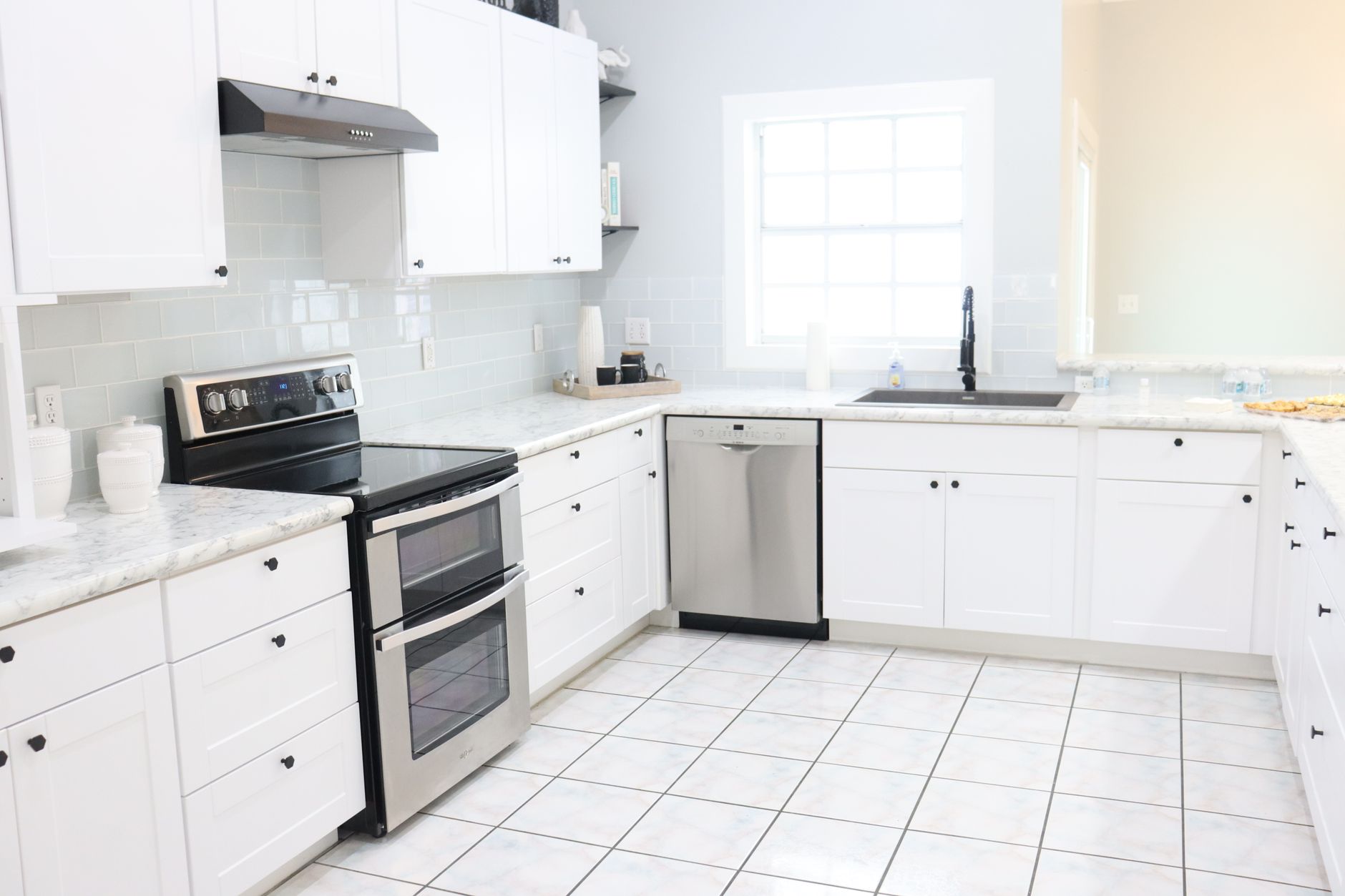 A bright and spacious modern kitchen with white cabinets, appliances, and natural light, illustrating The Kitchen Work Triangle: Does Feng Shui Agree With It