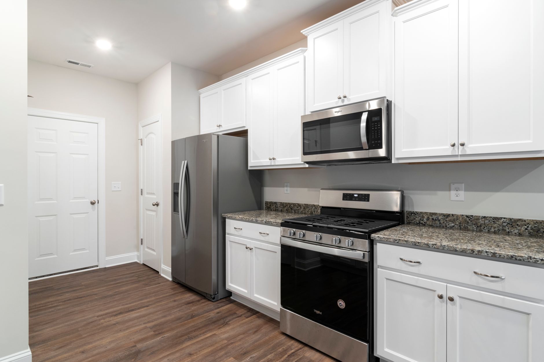 Contemporary kitchen featuring stainless steel fridge and microwave with white cabinetry, illustrating The Kitchen Work Triangle: Does Feng Shui Agree With It