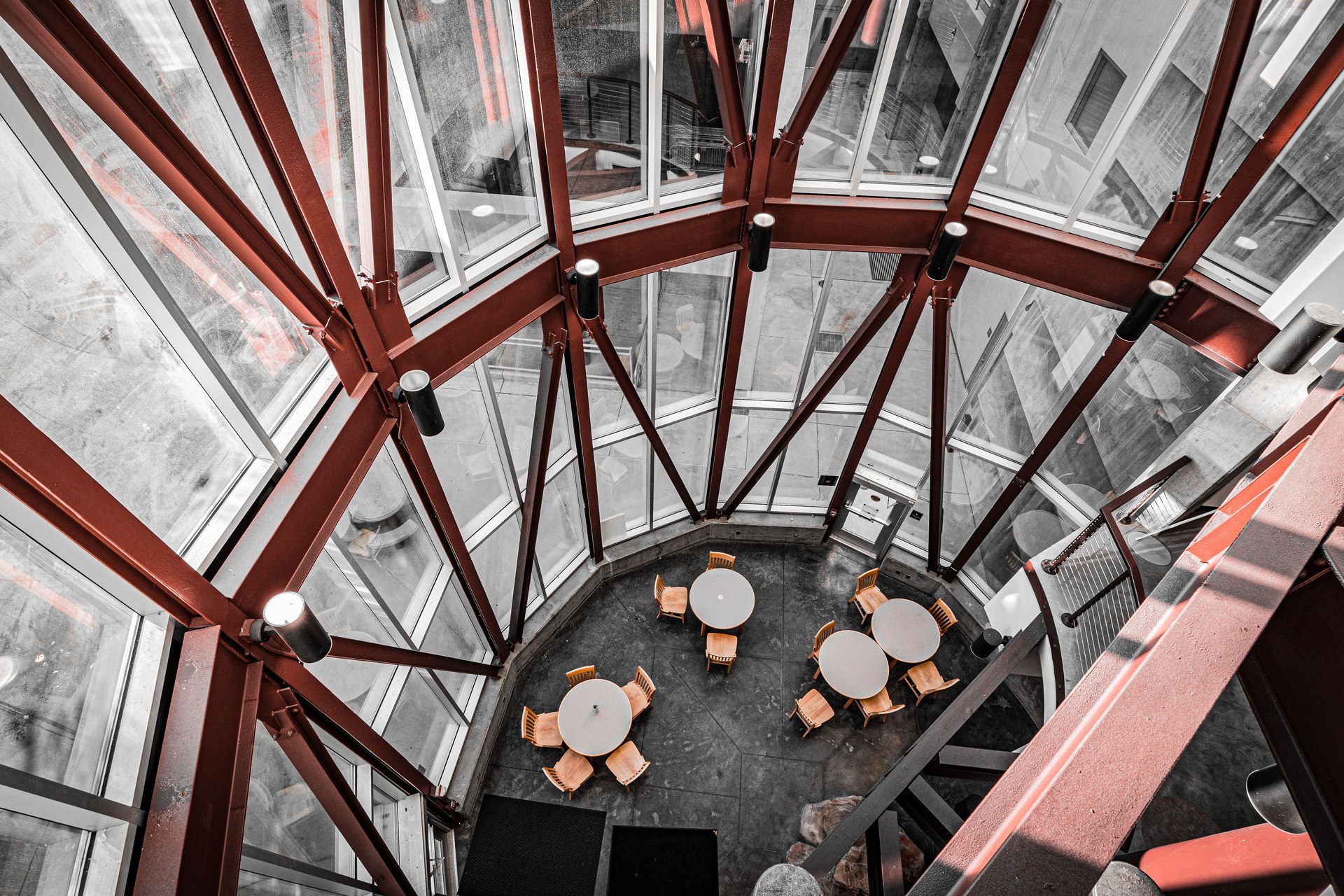 Aerial view of a modern dining area with round tables, wooden chairs, and large glass windows