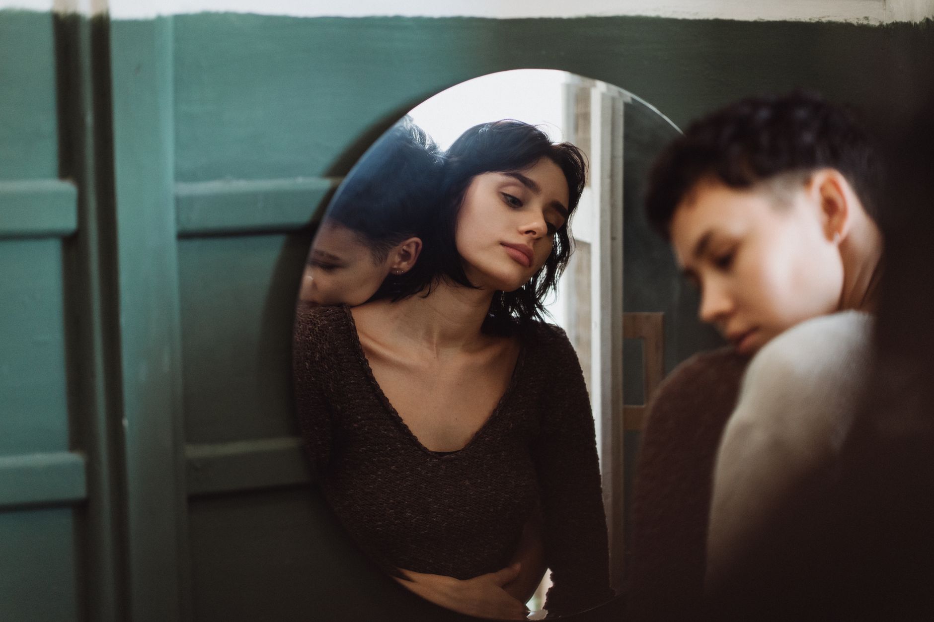 Two people sharing a reflective moment, captured through a mirror in an intimate setting, illustrating Mirror Facing the Bed: Is It Actually a Feng Shui Problem