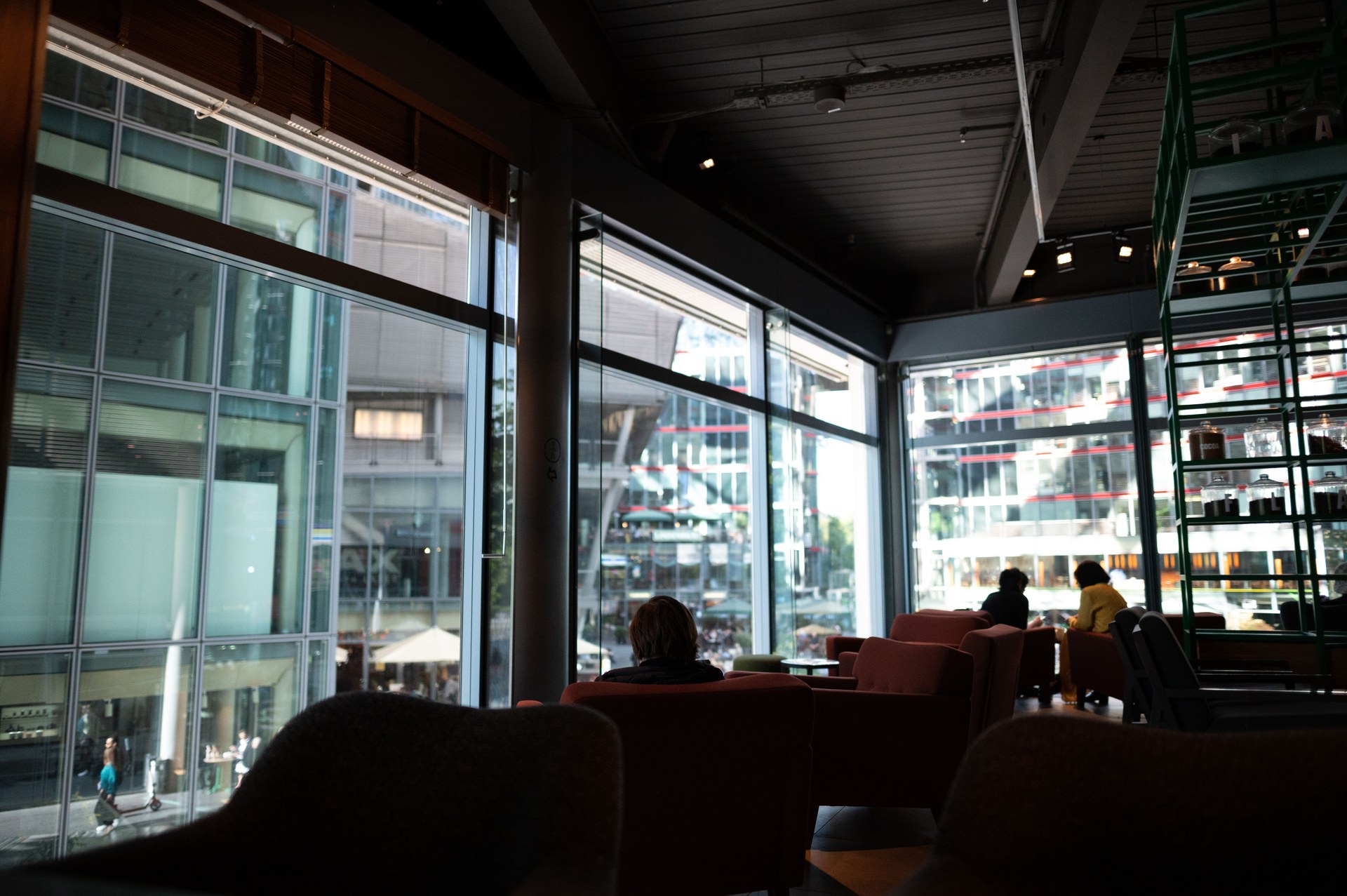 A contemporary cafe interior with large glass windows showcasing urban architecture outside