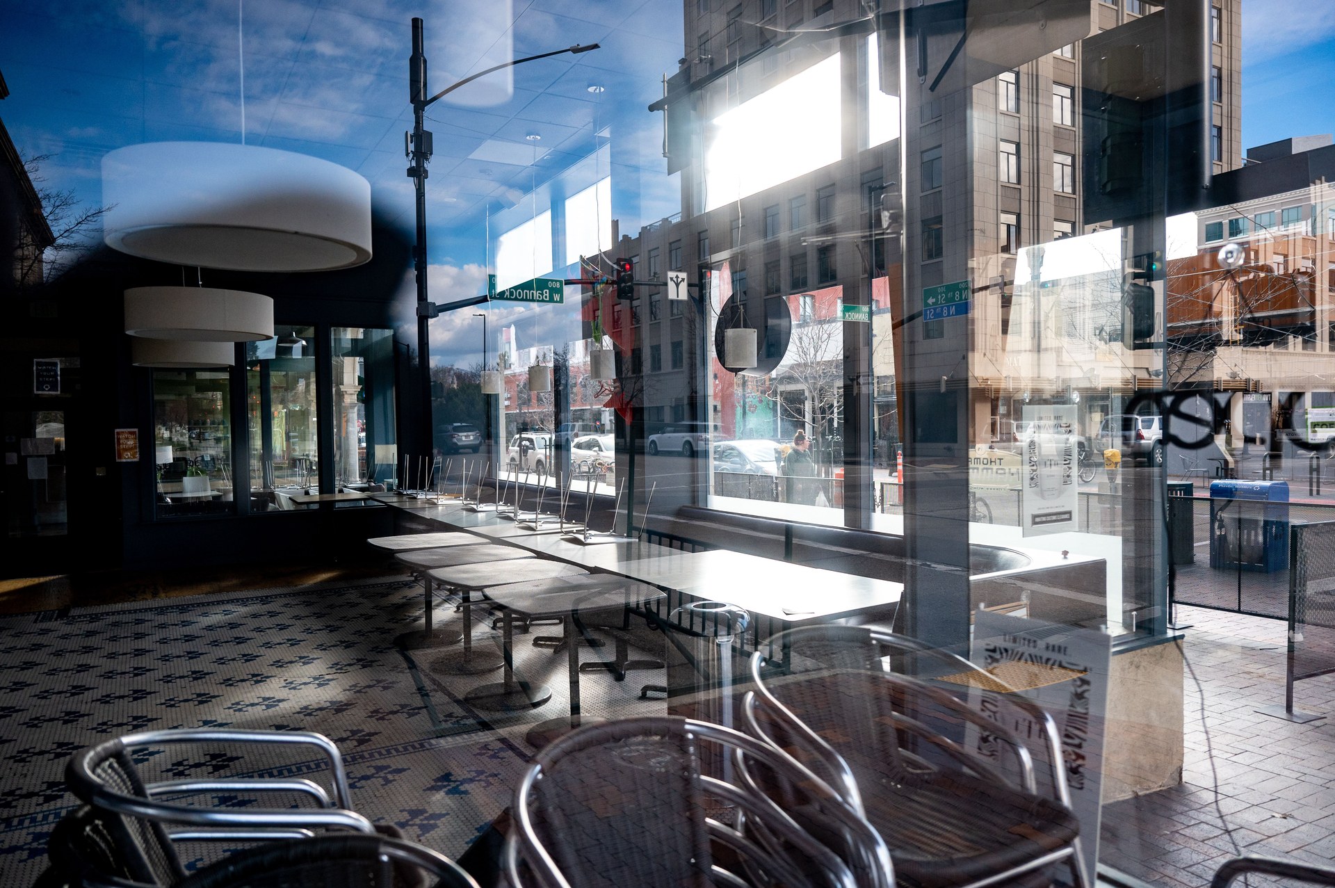 Modern cafe with reflections on glass windows, showcasing empty tables and urban street view