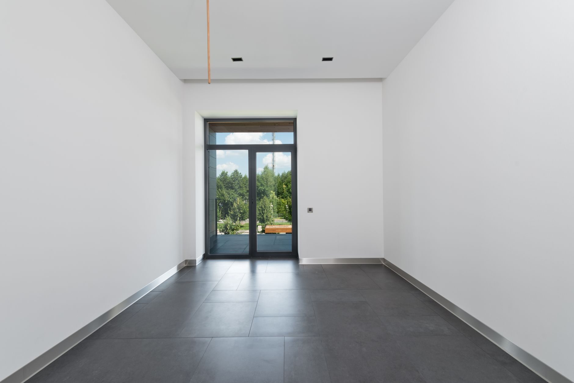 Interior of spacious room with tile flooring and white walls with glass doors in daylight, illustrating What Does Feng Shui Say About a Home's Previous Occupants