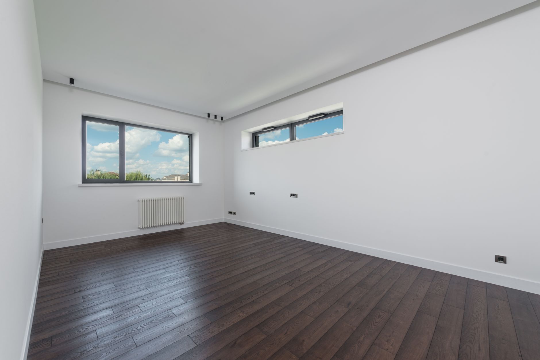 Interior of empty spacious room with laminated floor big windows white walls and ceiling in daylight, illustrating What Does Feng Shui Say About a Home's Previous Occupants