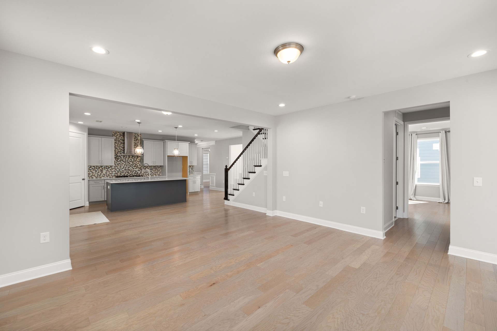 Spacious open-concept living room with hardwood floors and modern kitchen design