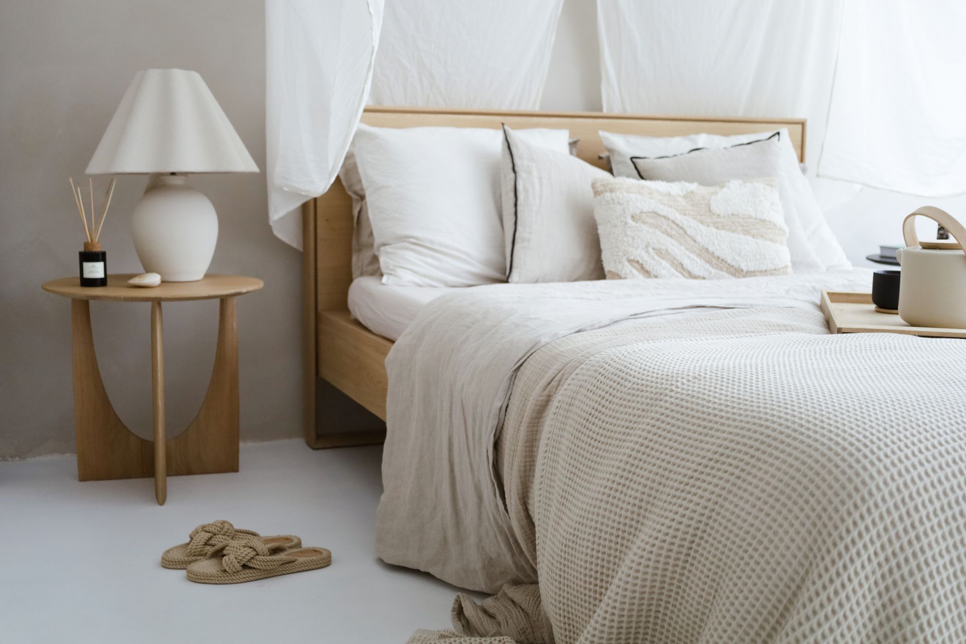 A minimalist bedroom with neutral tones featuring cozy bedding, a side table, and soft lighting, illustrating How Should a Room With Two Doors Be Arranged in Feng Shui
