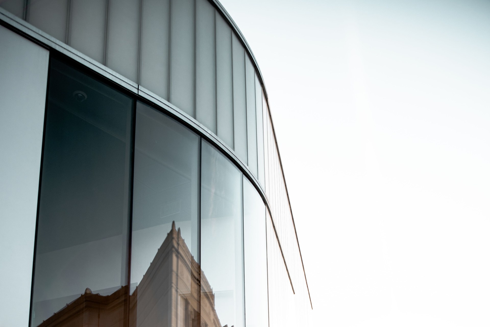 Contemporary building with glass facade reflecting architectural details under clear daylight