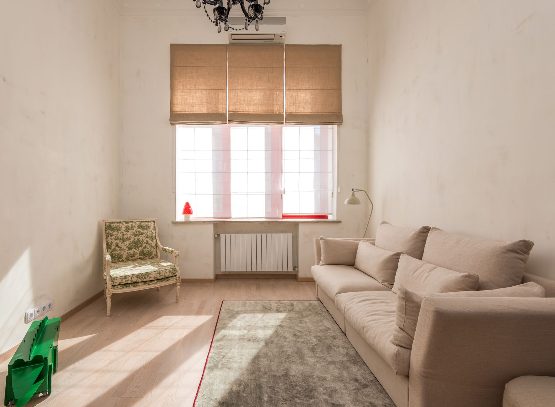 Bright, minimalist living room with beige sofa and classic armchair under warm natural light, illustrating What Is a "Secret Arrow" From Outside a Home