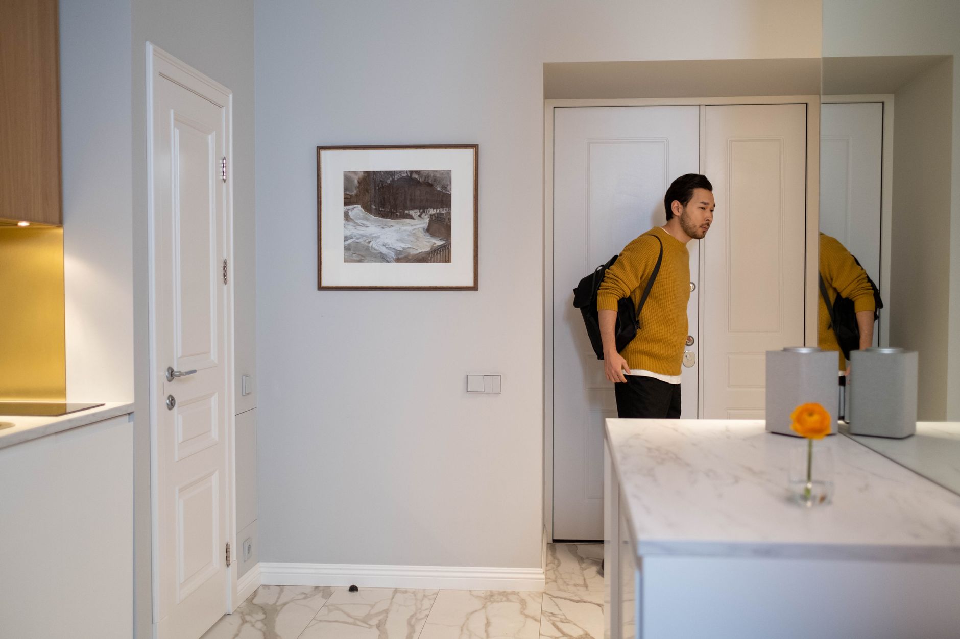 Asian man with bag entering a modern, well lit interior room with minimal decor, illustrating How to Separate Sleeping and Living Areas in One Room