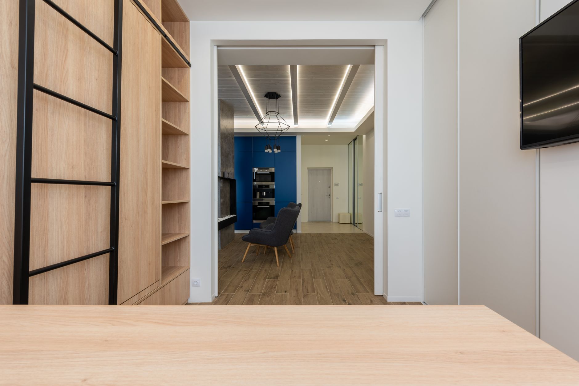 Interior of home office with wooden table and closet equipped with TV set and stylish kitchen, illustrating How to Separate Sleeping and Living Areas in One Room